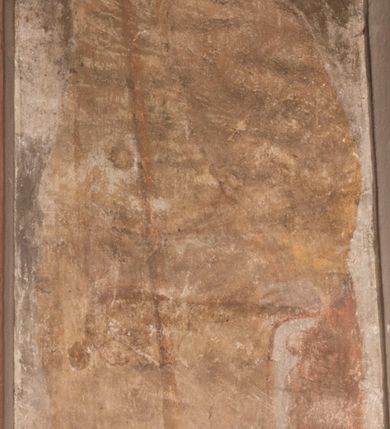 Zdjęcie nr 7: Malowidła z przedstawieniem św. Michała Archanioła pokonującego szatana i św. Jerzego walczącego ze smokiem zostały wykonane na ścianie północnej w dwóch wnękach podokiennych. Obie kompozycje powstały w polach o kształcie wydłużonego prostokąta. Święty Michał Archanioł został przedstawiony frontalnie w całej postaci z głową w ujęciu trzech czwartych w lewo. W uniesionej ponad głowę prawej ręce trzyma włócznię, wbitą w deptanego pod nogami szatana, którą jednocześnie podtrzymuje lewą ręką. Z tyłu widać jego rozpostarte skrzydła, skrzyżowane nad głową. Archanioł ma owalną twarz o wydatnym nosie oraz jasne włosy spływające na ramiona. Ubrany jest w przepasaną  tunikę sięgającą goleni i w narzucony na ramiona płaszcz. Postać diabła pod jego stopami obutymi w buty jest prawie niewidoczna. W podobny sposób przedstawiono św. Jerzego. Święty został ukazany frontalnie na rozstawionych nogach w całej postaci ujętej w kontrapoście z głową w trzech czwartych skierowaną w lewo. Prawą rękę ma uniesioną ponad głową i zgiętą w łokciu. Trzyma w niej lancę podtrzymywaną lewą ręką. Pod jego stopami widoczny jest zarys zwiniętego smoka o zarysie bazyliszka. Św. Jerzy ubrany jest w strój rycerski. Na głowie ma spiczasto zakończony hełm z kolczugą. Ciało okrywa mocno taliowana w pasie tunika zdobiona u dołu ornamentem z motywem trójkąta równoramiennego. Na nogach ma założone wysokie buty. W obu przedstawieniach widoczne są ciemne ugry, ciemna czerwień, żółcień, błękit i brąz. Tła są szare. 