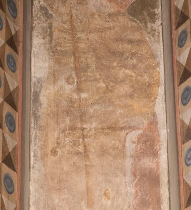 Zdjęcie nr 4: Malowidła z przedstawieniem św. Michała Archanioła pokonującego szatana i św. Jerzego walczącego ze smokiem zostały wykonane na ścianie północnej w dwóch wnękach podokiennych. Obie kompozycje powstały w polach o kształcie wydłużonego prostokąta. Święty Michał Archanioł został przedstawiony frontalnie w całej postaci z głową w ujęciu trzech czwartych w lewo. W uniesionej ponad głowę prawej ręce trzyma włócznię, wbitą w deptanego pod nogami szatana, którą jednocześnie podtrzymuje lewą ręką. Z tyłu widać jego rozpostarte skrzydła, skrzyżowane nad głową. Archanioł ma owalną twarz o wydatnym nosie oraz jasne włosy spływające na ramiona. Ubrany jest w przepasaną  tunikę sięgającą goleni i w narzucony na ramiona płaszcz. Postać diabła pod jego stopami obutymi w buty jest prawie niewidoczna. W podobny sposób przedstawiono św. Jerzego. Święty został ukazany frontalnie na rozstawionych nogach w całej postaci ujętej w kontrapoście z głową w trzech czwartych skierowaną w lewo. Prawą rękę ma uniesioną ponad głową i zgiętą w łokciu. Trzyma w niej lancę podtrzymywaną lewą ręką. Pod jego stopami widoczny jest zarys zwiniętego smoka o zarysie bazyliszka. Św. Jerzy ubrany jest w strój rycerski. Na głowie ma spiczasto zakończony hełm z kolczugą. Ciało okrywa mocno taliowana w pasie tunika zdobiona u dołu ornamentem z motywem trójkąta równoramiennego. Na nogach ma założone wysokie buty. W obu przedstawieniach widoczne są ciemne ugry, ciemna czerwień, żółcień, błękit i brąz. Tła są szare. 