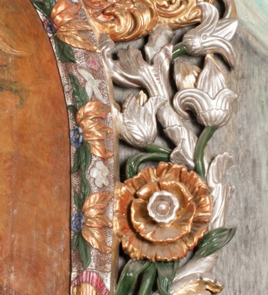 Zdjęcie nr 22: Obraz w formie stojącego prostokąta zamkniętego łukiem półkolistym. W centrum siedząca Matka Boska ukazana do kolan, frontalnie, lewym ramieniem obejmuje siedzące na jej kolanie Dzieciątko, w prawej ręce z przodu trzyma berło. Twarz ma owalną, o delikatnych rysach, dużych, migdałowatych oczach, długim, prostym nosie i niewielkich, pełnych ustach, okoloną długimi brązowymi włosami, opadającymi na ramiona. Ubrana jest w różową suknię, marszczoną przy dekolcie, z dekoracyjną lamówką oraz w obfity ciemnoniebieski płaszcz zarzucony na ramiona i opadający na kolana, ze złoconą lamówką i gwiazdą na prawym barku. Na głowie ma koronę otwartą, wokół nimb gwieździsty. Dzieciątko w pozycji siedzącej, zwrócone w trzech czwartych w prawo, w lewej ręce trzyma jabłko królewskie, prawą unosi w geście błogosławieństwa. Twarz ma kwadratową o pełnych policzkach, migdałowatych oczach, małym nosie i pełnych ustach, okoloną jasnymi, kręconymi włosami. Ubrane jest w fioletową tunikę oraz czerwony płaszcz przerzucony przez kolana. Na głowie ma koronę otwartą. Postacie ukazane na pomarańczowo-brązowym tle, koncentrycznie rozjaśnionym wokół głowy Marii, którą flankują dwa niewielkie anioły z rękami złożonymi w geście modlitwy. Obraz ujęty ornamentalną ramą utworzoną z wici roślinnej przeplatanej kwiatami, tworzącą nad łukiem szczyt z medalionem w wieńcu laurowym, ze skrzyżowanymi laskami marszałkowskimi w polu zwieńczonym koroną zamkniętą. W dolnej partii ramy płaskorzeźbione przedstawienie Chrystusa i Samarytanki przy studni z inicjałami „T(homas) O(linski) D(ecanus) W(ielicensis) P(lebanus) N(iepolomicensis) V(ir) I(llustris)”. 

