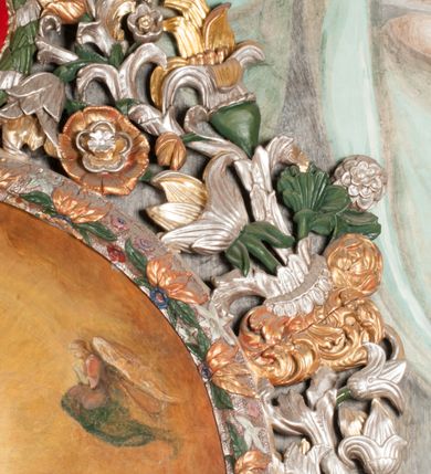 Zdjęcie nr 19: Obraz w formie stojącego prostokąta zamkniętego łukiem półkolistym. W centrum siedząca Matka Boska ukazana do kolan, frontalnie, lewym ramieniem obejmuje siedzące na jej kolanie Dzieciątko, w prawej ręce z przodu trzyma berło. Twarz ma owalną, o delikatnych rysach, dużych, migdałowatych oczach, długim, prostym nosie i niewielkich, pełnych ustach, okoloną długimi brązowymi włosami, opadającymi na ramiona. Ubrana jest w różową suknię, marszczoną przy dekolcie, z dekoracyjną lamówką oraz w obfity ciemnoniebieski płaszcz zarzucony na ramiona i opadający na kolana, ze złoconą lamówką i gwiazdą na prawym barku. Na głowie ma koronę otwartą, wokół nimb gwieździsty. Dzieciątko w pozycji siedzącej, zwrócone w trzech czwartych w prawo, w lewej ręce trzyma jabłko królewskie, prawą unosi w geście błogosławieństwa. Twarz ma kwadratową o pełnych policzkach, migdałowatych oczach, małym nosie i pełnych ustach, okoloną jasnymi, kręconymi włosami. Ubrane jest w fioletową tunikę oraz czerwony płaszcz przerzucony przez kolana. Na głowie ma koronę otwartą. Postacie ukazane na pomarańczowo-brązowym tle, koncentrycznie rozjaśnionym wokół głowy Marii, którą flankują dwa niewielkie anioły z rękami złożonymi w geście modlitwy. Obraz ujęty ornamentalną ramą utworzoną z wici roślinnej przeplatanej kwiatami, tworzącą nad łukiem szczyt z medalionem w wieńcu laurowym, ze skrzyżowanymi laskami marszałkowskimi w polu zwieńczonym koroną zamkniętą. W dolnej partii ramy płaskorzeźbione przedstawienie Chrystusa i Samarytanki przy studni z inicjałami „T(homas) O(linski) D(ecanus) W(ielicensis) P(lebanus) N(iepolomicensis) V(ir) I(llustris)”. 

