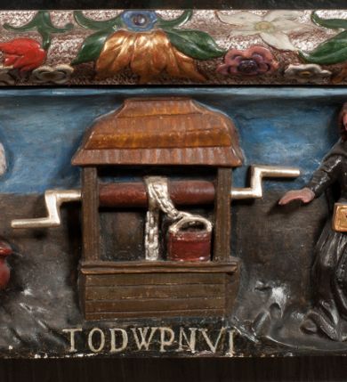 Zdjęcie nr 24: Obraz w formie stojącego prostokąta zamkniętego łukiem półkolistym. W centrum siedząca Matka Boska ukazana do kolan, frontalnie, lewym ramieniem obejmuje siedzące na jej kolanie Dzieciątko, w prawej ręce z przodu trzyma berło. Twarz ma owalną, o delikatnych rysach, dużych, migdałowatych oczach, długim, prostym nosie i niewielkich, pełnych ustach, okoloną długimi brązowymi włosami, opadającymi na ramiona. Ubrana jest w różową suknię, marszczoną przy dekolcie, z dekoracyjną lamówką oraz w obfity ciemnoniebieski płaszcz zarzucony na ramiona i opadający na kolana, ze złoconą lamówką i gwiazdą na prawym barku. Na głowie ma koronę otwartą, wokół nimb gwieździsty. Dzieciątko w pozycji siedzącej, zwrócone w trzech czwartych w prawo, w lewej ręce trzyma jabłko królewskie, prawą unosi w geście błogosławieństwa. Twarz ma kwadratową o pełnych policzkach, migdałowatych oczach, małym nosie i pełnych ustach, okoloną jasnymi, kręconymi włosami. Ubrane jest w fioletową tunikę oraz czerwony płaszcz przerzucony przez kolana. Na głowie ma koronę otwartą. Postacie ukazane na pomarańczowo-brązowym tle, koncentrycznie rozjaśnionym wokół głowy Marii, którą flankują dwa niewielkie anioły z rękami złożonymi w geście modlitwy. Obraz ujęty ornamentalną ramą utworzoną z wici roślinnej przeplatanej kwiatami, tworzącą nad łukiem szczyt z medalionem w wieńcu laurowym, ze skrzyżowanymi laskami marszałkowskimi w polu zwieńczonym koroną zamkniętą. W dolnej partii ramy płaskorzeźbione przedstawienie Chrystusa i Samarytanki przy studni z inicjałami „T(homas) O(linski) D(ecanus) W(ielicensis) P(lebanus) N(iepolomicensis) V(ir) I(llustris)”. 

