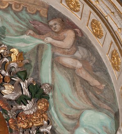 Zdjęcie nr 31: Obraz w formie stojącego prostokąta zamkniętego łukiem półkolistym. W centrum siedząca Matka Boska ukazana do kolan, frontalnie, lewym ramieniem obejmuje siedzące na jej kolanie Dzieciątko, w prawej ręce z przodu trzyma berło. Twarz ma owalną, o delikatnych rysach, dużych, migdałowatych oczach, długim, prostym nosie i niewielkich, pełnych ustach, okoloną długimi brązowymi włosami, opadającymi na ramiona. Ubrana jest w różową suknię, marszczoną przy dekolcie, z dekoracyjną lamówką oraz w obfity ciemnoniebieski płaszcz zarzucony na ramiona i opadający na kolana, ze złoconą lamówką i gwiazdą na prawym barku. Na głowie ma koronę otwartą, wokół nimb gwieździsty. Dzieciątko w pozycji siedzącej, zwrócone w trzech czwartych w prawo, w lewej ręce trzyma jabłko królewskie, prawą unosi w geście błogosławieństwa. Twarz ma kwadratową o pełnych policzkach, migdałowatych oczach, małym nosie i pełnych ustach, okoloną jasnymi, kręconymi włosami. Ubrane jest w fioletową tunikę oraz czerwony płaszcz przerzucony przez kolana. Na głowie ma koronę otwartą. Postacie ukazane na pomarańczowo-brązowym tle, koncentrycznie rozjaśnionym wokół głowy Marii, którą flankują dwa niewielkie anioły z rękami złożonymi w geście modlitwy. Obraz ujęty ornamentalną ramą utworzoną z wici roślinnej przeplatanej kwiatami, tworzącą nad łukiem szczyt z medalionem w wieńcu laurowym, ze skrzyżowanymi laskami marszałkowskimi w polu zwieńczonym koroną zamkniętą. W dolnej partii ramy płaskorzeźbione przedstawienie Chrystusa i Samarytanki przy studni z inicjałami „T(homas) O(linski) D(ecanus) W(ielicensis) P(lebanus) N(iepolomicensis) V(ir) I(llustris)”. 

