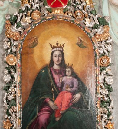 Zdjęcie nr 2: Obraz w formie stojącego prostokąta zamkniętego łukiem półkolistym. W centrum siedząca Matka Boska ukazana do kolan, frontalnie, lewym ramieniem obejmuje siedzące na jej kolanie Dzieciątko, w prawej ręce z przodu trzyma berło. Twarz ma owalną, o delikatnych rysach, dużych, migdałowatych oczach, długim, prostym nosie i niewielkich, pełnych ustach, okoloną długimi brązowymi włosami, opadającymi na ramiona. Ubrana jest w różową suknię, marszczoną przy dekolcie, z dekoracyjną lamówką oraz w obfity ciemnoniebieski płaszcz zarzucony na ramiona i opadający na kolana, ze złoconą lamówką i gwiazdą na prawym barku. Na głowie ma koronę otwartą, wokół nimb gwieździsty. Dzieciątko w pozycji siedzącej, zwrócone w trzech czwartych w prawo, w lewej ręce trzyma jabłko królewskie, prawą unosi w geście błogosławieństwa. Twarz ma kwadratową o pełnych policzkach, migdałowatych oczach, małym nosie i pełnych ustach, okoloną jasnymi, kręconymi włosami. Ubrane jest w fioletową tunikę oraz czerwony płaszcz przerzucony przez kolana. Na głowie ma koronę otwartą. Postacie ukazane na pomarańczowo-brązowym tle, koncentrycznie rozjaśnionym wokół głowy Marii, którą flankują dwa niewielkie anioły z rękami złożonymi w geście modlitwy. Obraz ujęty ornamentalną ramą utworzoną z wici roślinnej przeplatanej kwiatami, tworzącą nad łukiem szczyt z medalionem w wieńcu laurowym, ze skrzyżowanymi laskami marszałkowskimi w polu zwieńczonym koroną zamkniętą. W dolnej partii ramy płaskorzeźbione przedstawienie Chrystusa i Samarytanki przy studni z inicjałami „T(homas) O(linski) D(ecanus) W(ielicensis) P(lebanus) N(iepolomicensis) V(ir) I(llustris)”. 

