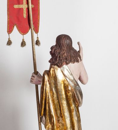 Zdjęcie nr 2: Pełnoplastyczna rzeźba przedstawia Chrystusa Zmartwychwstałego, stojącego w lekkim kontrapoście, z ciężarem ciała wspartym na lewej nodze, która depcze węża trzymającego w paszczy jabłko. Zbawiciel prawą nogę lekko ugina w kolanie opierając ją na ludzkiej czaszce. Chrystus w lewej ręce trzyma złotą laskę krzyżową z podwieszoną chorągwią, prawą zaś unosi w geście błogosławieństwa. Ma owalną twarz z prostym nosem, z uniesionymi ku górze brązowymi oczami i jasnoróżowymi ustami. Jego głowę okalają długie, brązowe włosy opadające na ramiona w lekkich lokach oraz krótka, brązowa broda. Zmartwychwstały ubrany jest w złocony płaszcz ze srebrną podszewką, odsłaniający prawe ramię, przerzucony z przodu przez lewą rękę i opadający miękkimi fałdami zakrywając prawy bok postaci. Karnacja ciała jest bladoróżowa. Na dłoniach, boku oraz stopach widoczne są czerwone rany po gwoździach i lancy. 