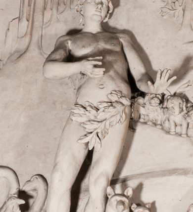 Zdjęcie nr 27: Pełnoplastyczna figura Chrystusa Ukrzyżowanego umieszczona jest na belce tęczowej. Chrystus został ukazany na krzyżu w dużym zwisie na wyprężonych ramionach, tworzących kształt litery „V”. Jego korpus jest wydłużony i esowato wygięty z silnym zaznaczeniem modelunku anatomicznego. Nogi zostały lekko zgięte w kolanach i nieznacznie odchylone w bok, zaś stopy skrzyżowane i przybite jednym gwoździem do krzyża. Wyeksponowano muskulaturę kończyn, żebra i ranę w boku. Głowa Zbawiciela opada na prawe ramię. Jego twarz jest podłużna, z długim, prostym nosem, o zamkniętych oczach i otwartych ustach w grymasie bólu. Otacza ją gęsta, kręcona broda oraz długie, ciemne włosy opadające lokami na oba ramiona. Na głowie widoczna jest cierniowa korona o długich kolcach. Biodra Zbawiciela zostały przepasane długim perizonium sięgającym kolan. Jest ono na środku drapowane za pomocą misowych fałd układających się poprzecznie, zaś po bokach zostało wywinięte za pomocą dwóch festonów opadających kaskadowo wzdłuż ud. Ponad głową Chrystusa umieszczony jest złocony titulus o kształtach barokowych w formie kartusza z napisem „INRI”.Rzeźba jest polichromowana, a perizonium srebrzone z zastosowaniem laserunków.