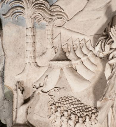 Zdjęcie nr 36: Pełnoplastyczna figura Chrystusa Ukrzyżowanego umieszczona jest na belce tęczowej. Chrystus został ukazany na krzyżu w dużym zwisie na wyprężonych ramionach, tworzących kształt litery „V”. Jego korpus jest wydłużony i esowato wygięty z silnym zaznaczeniem modelunku anatomicznego. Nogi zostały lekko zgięte w kolanach i nieznacznie odchylone w bok, zaś stopy skrzyżowane i przybite jednym gwoździem do krzyża. Wyeksponowano muskulaturę kończyn, żebra i ranę w boku. Głowa Zbawiciela opada na prawe ramię. Jego twarz jest podłużna, z długim, prostym nosem, o zamkniętych oczach i otwartych ustach w grymasie bólu. Otacza ją gęsta, kręcona broda oraz długie, ciemne włosy opadające lokami na oba ramiona. Na głowie widoczna jest cierniowa korona o długich kolcach. Biodra Zbawiciela zostały przepasane długim perizonium sięgającym kolan. Jest ono na środku drapowane za pomocą misowych fałd układających się poprzecznie, zaś po bokach zostało wywinięte za pomocą dwóch festonów opadających kaskadowo wzdłuż ud. Ponad głową Chrystusa umieszczony jest złocony titulus o kształtach barokowych w formie kartusza z napisem „INRI”.Rzeźba jest polichromowana, a perizonium srebrzone z zastosowaniem laserunków.