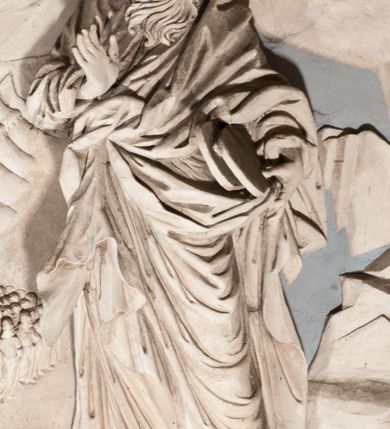 Zdjęcie nr 38: Pełnoplastyczna figura Chrystusa Ukrzyżowanego umieszczona jest na belce tęczowej. Chrystus został ukazany na krzyżu w dużym zwisie na wyprężonych ramionach, tworzących kształt litery „V”. Jego korpus jest wydłużony i esowato wygięty z silnym zaznaczeniem modelunku anatomicznego. Nogi zostały lekko zgięte w kolanach i nieznacznie odchylone w bok, zaś stopy skrzyżowane i przybite jednym gwoździem do krzyża. Wyeksponowano muskulaturę kończyn, żebra i ranę w boku. Głowa Zbawiciela opada na prawe ramię. Jego twarz jest podłużna, z długim, prostym nosem, o zamkniętych oczach i otwartych ustach w grymasie bólu. Otacza ją gęsta, kręcona broda oraz długie, ciemne włosy opadające lokami na oba ramiona. Na głowie widoczna jest cierniowa korona o długich kolcach. Biodra Zbawiciela zostały przepasane długim perizonium sięgającym kolan. Jest ono na środku drapowane za pomocą misowych fałd układających się poprzecznie, zaś po bokach zostało wywinięte za pomocą dwóch festonów opadających kaskadowo wzdłuż ud. Ponad głową Chrystusa umieszczony jest złocony titulus o kształtach barokowych w formie kartusza z napisem „INRI”.Rzeźba jest polichromowana, a perizonium srebrzone z zastosowaniem laserunków.