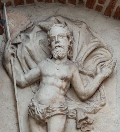 Zdjęcie nr 3: Płaskorzeźbione przedstawienie Chrystusa Zmartwychwstałego ukazanego w całej postaci, w trzech czwartych w prawo, w wykroku, z prawą nogą zgiętą w kolanie. W prawej, uniesionej ręce trzyma chorągiew z białym krzyżem na czerwonym tle, lewa uniesiona do góry w geście błogosławieństwa. Twarz owalna, pociągła, z migdałowatymi oczami i prostym nosem, okolona falowaną brodą i włosami sięgającymi ramion. Chrystus przez biodra ma przewiązane krótkie, obficie fałdowane perizonium, z rozwianym na lewym boku fragmentem. Pod szyją ma zapięty płaszcz rozwiany z tyłu postaci. Ciało krępe, muskularne, z podkreślonymi mięśniami klatki piersiowej. Postać umieszczona na profilowanym postumencie z tablicą z inskrypcją „EGO SVM RESVR/RECTIO ET VITA / IOAN(NES) CAP(UT) XI”.