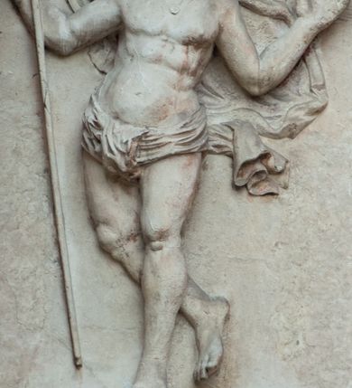 Zdjęcie nr 2: Płaskorzeźbione przedstawienie Chrystusa Zmartwychwstałego ukazanego w całej postaci, w trzech czwartych w prawo, w wykroku, z prawą nogą zgiętą w kolanie. W prawej, uniesionej ręce trzyma chorągiew z białym krzyżem na czerwonym tle, lewa uniesiona do góry w geście błogosławieństwa. Twarz owalna, pociągła, z migdałowatymi oczami i prostym nosem, okolona falowaną brodą i włosami sięgającymi ramion. Chrystus przez biodra ma przewiązane krótkie, obficie fałdowane perizonium, z rozwianym na lewym boku fragmentem. Pod szyją ma zapięty płaszcz rozwiany z tyłu postaci. Ciało krępe, muskularne, z podkreślonymi mięśniami klatki piersiowej. Postać umieszczona na profilowanym postumencie z tablicą z inskrypcją „EGO SVM RESVR/RECTIO ET VITA / IOAN(NES) CAP(UT) XI”.