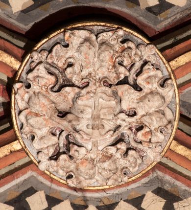 Zdjęcie nr 1: Rzeźbiony zwornik z przedstawieniem maski liściastej – twarzy ludzkiej wśród elementów roślinnych, liście wydobywają się z ust i przysłaniają policzki postaci.