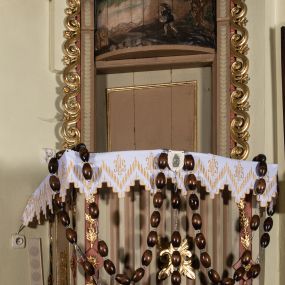 Zdjęcie nr 1: Ambona wisząca, przyścienna, z wejściem przez zaplecek od zakrystii. Kosz na planie prostokąta o wypukłej ścianie frontowej, na cokole w formie wałka, z podwieszeniem w kształcie ściętego ostrosłupa o wklęsłych bokach, zakończonego szyszką. Naroża kosza ujęte pilastrami z płycinami w trzonach, zdobionymi kampanulami, podtrzymującymi parapet w formie gzymsu. Ścianka frontowa dekorowana kanelurami, boczne prostokątnymi płycinami z rozetami. Zaplecek w formie stojącego prostokąta, ujęty listwami z cekinami oraz uszami utworzonymi z wijącego się ornamentu roślinnego. W polu drzwi, ponad którymi wypukła płaskorzeźba w formie leżącego prostokąta, z przedstawieniem siewcy na tle pejzażu. Baldachim na planie analogicznym względem kosza, z podwieszonymi lambrekinami, na nim cokół, na którym leży otwarta księga pośród obłoków, z dwiema uskrzydlonymi główkami anielskimi, w glorii promienistej. Nad nimi krzyż. Księga z napisem „LEX / ET / EVAN/GELIUM / I / II / III / IV / V / VI / VII / VIII / IX / X”. Na podniebieniu baldachimu gołębica Ducha Świętego. Z tyłu, na drzwiczkach widniał napis „I.K. 1831”. Struktura polichromowana w kolorze beżowym, jasnobrązowym i jasnoróżowym, ornamentyka złocona, detal srebrzony. 


