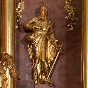 Zdjęcie nr 1: Rzeźba drążona, ustawiona na podstawie na plenie prostokąta. Święty ukazany frontalnie, z głową skierowaną w prawo, w kontrapoście, o delikatnie odchylonej w tył sylwetce. Prawą rękę kładzie na piersi, w lewej, odsuniętej od boku trzyma miecz skierowany ostrzem w dół. Twarz ma pociągłą, szczupłą, o wysokim czole, małych, migdałowatych oczach, prostym nosie i otwartych ustach, okoloną długą, kręconą brodą i krótkimi włosami, z pojedynczym puklem nad czołem i łysiną na głowie. Ubrany jest w tunikę przewiązaną pasem, ściśle przylegającą do ciała, z wywiniętymi mankietami oraz płaszcz zawieszony na lewym ramieniu, opadający na plecy, zawijający się na prawej nodze i zawiązany u pasa. Figura w całości złocona, ostrze miecza srebrzone.