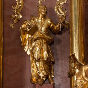 Zdjęcie nr 1: Rzeźba drążona, ustawiona na nieregularnej podstawie. Święty ukazany frontalnie, z głową skierowaną w lewo, w kontrapoście. Lewą rękę ma ugiętą i uniesioną w bok, w dłoni trzyma klucze, prawą ugiętą, przy boku, w której trzyma zamkniętą księgę. Twarz ma pociągłą, szczupłą, o małych, migdałowatych oczach, prostym nosie i pełnych, rozchylonych ustach, okoloną krótką, kręconą brodą i włosami. Ubrany jest w tunikę, rozchyloną na piersi, ściśle przylegająca do ciała, przepasaną w talii oraz obfity płaszcz zarzucony na prawe ramię i zawinięty na lewym boku i z przodu postaci. Figura w całości złocona.