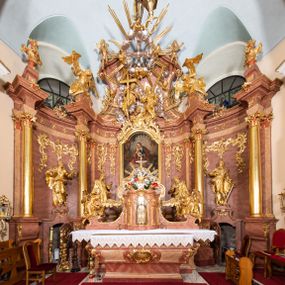Zdjęcie nr 1: Nastawa ołtarzowa architektoniczna, jednokondygnacyjna ze zwieńczeniem, pięcioosiowa, ustawiona na wysokim cokole. Ołtarz wolnostojący, drewniany, sarkofagowy, wklęsło-wypukły, o zdwojonym froncie; mensa drewniana z marmurowym portatylem. Od frontu rocaille'owy kartusz ujęty fantazyjnymi płycinami oraz liśćmi. Na ołtarzu tabernakulum w formie sześcianu o wklęsłych bokach i wklęsło-wypukłym froncie; ujęte w narożach dwiema parami pilastrów o trzonach przechodzących w spływy wolutowe zdobione rocaille'm i różami. Pilastry podtrzymują falujący gzyms oraz fragmenty falistego, przerwanego, odwróconego przyczółka, przechodzącego w cokół, stanowiący tron wystawienia, na którym stoi krucyfiks. Na ściance frontowej obrotowa nisza, o wykroju stojącego prostokąta zamkniętego łukiem półkolistym, w opasce, zwieńczona kampanulami. W jej polu drzwiczki w formie stojącego prostokąta zamkniętego łukiem półkolistym w profilowanej ramie, z odlewanym przedstawieniem baranka leżącego na księdze z pieczęciami. Tabernakulum ujęte spływami przechodzącymi na krańcach we fragmenty wolutowego gzymsu, na których siedzą figury adorujących aniołów. Ponad tabernakulum fantazyjna ścianka tworząca tło dla tronu wystawienia z prześwitem otoczonym obłokami, z glorią promienistą, flankowana rocaille'owymi uszami. Cokół nastawy z wyodrębnionymi dwoma prostopadłościanami i dwoma konsolami, na dwóch skrajnych osiach bramki zamknięte wolutowymi szczytami tworzącymi cokoły dla figur, z przejściami w formie stojącego prostokąta zamkniętego łukiem odcinkowym nadwieszonym, z drzwiczkami. Cokół i drzwiczki dekorowane rocaille'm. Lico nastawy wklęsłe, osie wydzielone trzema parami pilastrów, na których tle stoją dwie pary kolumn o kapitelach kompozytowych. Podpory dźwigają pełne belkowanie, wyłamane na ich osi, przerwane nad polem środkowym, o gzymsie przechodzącym miejscami w rocaille'owe kartusze. Na osi środkowej wnęka z obrazem Matki Boskiej Wspomożenia Wiernych, w formie stojącego prostokąta zamkniętego łukiem odcinkowym nadwieszonym z uskokiem, ujęta profilowaną ramą, dekorowaną ponad łukiem płomienistym rocaille'm. Na pozostałych czterech osiach figury św. Barbary, św. Apolonii, św. Piotra i św. Pawła ustawione na rokokowych wspornikach. Trzony pilastrów i pola osi bocznych wypełnione rocaille'm, fryz dekorowany zwisami kwiatowymi. Zwieńczenie w formie zbliżonej do trapezu, zamknięte dwoma fragmentami gzymsu przechodzącego w woluty, flankowane wolutami spływającymi na belkowanie wewnętrznej pary kolumn, na których siedzą adorujące figury aniołów. W polu rzeźbiarska grupa Trójcy Świętej, pośród obłoków, w glorii promienistej, zwieńczona gołębicą Ducha Świętego w otoku z obłoków i uskrzydlonych główek anielskich, w glorii promienistej, flankowana przez dwa putta siedzące na gzymsie. Zwieńczenie po bokach obwiedzione rocaille'm, ujęte liśćmi palmowymi. Na belkowaniu, na osiach zewnętrznej pary kolumn wolutowe cokoły z rokokowymi wazonami. Struktura polichromowana na sposób imitujący marmoryzację w kolorze różowym i różowo-pomarańczowym, kolumny, profile i ornamentyka złocone, obłoki srebrzone. 


