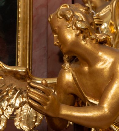 Zdjęcie nr 17: Nastawa ołtarzowa architektoniczna, jednokondygnacyjna ze zwieńczeniem, pięcioosiowa, ustawiona na wysokim cokole. Ołtarz wolnostojący, drewniany, sarkofagowy, wklęsło-wypukły, o zdwojonym froncie; mensa drewniana z marmurowym portatylem. Od frontu rocaille&#039;owy kartusz ujęty fantazyjnymi płycinami oraz liśćmi. Na ołtarzu tabernakulum w formie sześcianu o wklęsłych bokach i wklęsło-wypukłym froncie; ujęte w narożach dwiema parami pilastrów o trzonach przechodzących w spływy wolutowe zdobione rocaille&#039;m i różami. Pilastry podtrzymują falujący gzyms oraz fragmenty falistego, przerwanego, odwróconego przyczółka, przechodzącego w cokół, stanowiący tron wystawienia, na którym stoi krucyfiks. Na ściance frontowej obrotowa nisza, o wykroju stojącego prostokąta zamkniętego łukiem półkolistym, w opasce, zwieńczona kampanulami. W jej polu drzwiczki w formie stojącego prostokąta zamkniętego łukiem półkolistym w profilowanej ramie, z odlewanym przedstawieniem baranka leżącego na księdze z pieczęciami. Tabernakulum ujęte spływami przechodzącymi na krańcach we fragmenty wolutowego gzymsu, na których siedzą figury adorujących aniołów. Ponad tabernakulum fantazyjna ścianka tworząca tło dla tronu wystawienia z prześwitem otoczonym obłokami, z glorią promienistą, flankowana rocaille&#039;owymi uszami. Cokół nastawy z wyodrębnionymi dwoma prostopadłościanami i dwoma konsolami, na dwóch skrajnych osiach bramki zamknięte wolutowymi szczytami tworzącymi cokoły dla figur, z przejściami w formie stojącego prostokąta zamkniętego łukiem odcinkowym nadwieszonym, z drzwiczkami. Cokół i drzwiczki dekorowane rocaille&#039;m. Lico nastawy wklęsłe, osie wydzielone trzema parami pilastrów, na których tle stoją dwie pary kolumn o kapitelach kompozytowych. Podpory dźwigają pełne belkowanie, wyłamane na ich osi, przerwane nad polem środkowym, o gzymsie przechodzącym miejscami w rocaille&#039;owe kartusze. Na osi środkowej wnęka z obrazem Matki Boskiej Wspomożenia Wiernych, w formie stojącego prostokąta zamkniętego łukiem odcinkowym nadwieszonym z uskokiem, ujęta profilowaną ramą, dekorowaną ponad łukiem płomienistym rocaille&#039;m. Na pozostałych czterech osiach figury św. Barbary, św. Apolonii, św. Piotra i św. Pawła ustawione na rokokowych wspornikach. Trzony pilastrów i pola osi bocznych wypełnione rocaille&#039;m, fryz dekorowany zwisami kwiatowymi. Zwieńczenie w formie zbliżonej do trapezu, zamknięte dwoma fragmentami gzymsu przechodzącego w woluty, flankowane wolutami spływającymi na belkowanie wewnętrznej pary kolumn, na których siedzą adorujące figury aniołów. W polu rzeźbiarska grupa Trójcy Świętej, pośród obłoków, w glorii promienistej, zwieńczona gołębicą Ducha Świętego w otoku z obłoków i uskrzydlonych główek anielskich, w glorii promienistej, flankowana przez dwa putta siedzące na gzymsie. Zwieńczenie po bokach obwiedzione rocaille&#039;m, ujęte liśćmi palmowymi. Na belkowaniu, na osiach zewnętrznej pary kolumn wolutowe cokoły z rokokowymi wazonami. Struktura polichromowana na sposób imitujący marmoryzację w kolorze różowym i różowo-pomarańczowym, kolumny, profile i ornamentyka złocone, obłoki srebrzone. 

