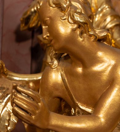 Zdjęcie nr 18: Nastawa ołtarzowa architektoniczna, jednokondygnacyjna ze zwieńczeniem, pięcioosiowa, ustawiona na wysokim cokole. Ołtarz wolnostojący, drewniany, sarkofagowy, wklęsło-wypukły, o zdwojonym froncie; mensa drewniana z marmurowym portatylem. Od frontu rocaille'owy kartusz ujęty fantazyjnymi płycinami oraz liśćmi. Na ołtarzu tabernakulum w formie sześcianu o wklęsłych bokach i wklęsło-wypukłym froncie; ujęte w narożach dwiema parami pilastrów o trzonach przechodzących w spływy wolutowe zdobione rocaille'm i różami. Pilastry podtrzymują falujący gzyms oraz fragmenty falistego, przerwanego, odwróconego przyczółka, przechodzącego w cokół, stanowiący tron wystawienia, na którym stoi krucyfiks. Na ściance frontowej obrotowa nisza, o wykroju stojącego prostokąta zamkniętego łukiem półkolistym, w opasce, zwieńczona kampanulami. W jej polu drzwiczki w formie stojącego prostokąta zamkniętego łukiem półkolistym w profilowanej ramie, z odlewanym przedstawieniem baranka leżącego na księdze z pieczęciami. Tabernakulum ujęte spływami przechodzącymi na krańcach we fragmenty wolutowego gzymsu, na których siedzą figury adorujących aniołów. Ponad tabernakulum fantazyjna ścianka tworząca tło dla tronu wystawienia z prześwitem otoczonym obłokami, z glorią promienistą, flankowana rocaille'owymi uszami. Cokół nastawy z wyodrębnionymi dwoma prostopadłościanami i dwoma konsolami, na dwóch skrajnych osiach bramki zamknięte wolutowymi szczytami tworzącymi cokoły dla figur, z przejściami w formie stojącego prostokąta zamkniętego łukiem odcinkowym nadwieszonym, z drzwiczkami. Cokół i drzwiczki dekorowane rocaille'm. Lico nastawy wklęsłe, osie wydzielone trzema parami pilastrów, na których tle stoją dwie pary kolumn o kapitelach kompozytowych. Podpory dźwigają pełne belkowanie, wyłamane na ich osi, przerwane nad polem środkowym, o gzymsie przechodzącym miejscami w rocaille'owe kartusze. Na osi środkowej wnęka z obrazem Matki Boskiej Wspomożenia Wiernych, w formie stojącego prostokąta zamkniętego łukiem odcinkowym nadwieszonym z uskokiem, ujęta profilowaną ramą, dekorowaną ponad łukiem płomienistym rocaille'm. Na pozostałych czterech osiach figury św. Barbary, św. Apolonii, św. Piotra i św. Pawła ustawione na rokokowych wspornikach. Trzony pilastrów i pola osi bocznych wypełnione rocaille'm, fryz dekorowany zwisami kwiatowymi. Zwieńczenie w formie zbliżonej do trapezu, zamknięte dwoma fragmentami gzymsu przechodzącego w woluty, flankowane wolutami spływającymi na belkowanie wewnętrznej pary kolumn, na których siedzą adorujące figury aniołów. W polu rzeźbiarska grupa Trójcy Świętej, pośród obłoków, w glorii promienistej, zwieńczona gołębicą Ducha Świętego w otoku z obłoków i uskrzydlonych główek anielskich, w glorii promienistej, flankowana przez dwa putta siedzące na gzymsie. Zwieńczenie po bokach obwiedzione rocaille'm, ujęte liśćmi palmowymi. Na belkowaniu, na osiach zewnętrznej pary kolumn wolutowe cokoły z rokokowymi wazonami. Struktura polichromowana na sposób imitujący marmoryzację w kolorze różowym i różowo-pomarańczowym, kolumny, profile i ornamentyka złocone, obłoki srebrzone. 

