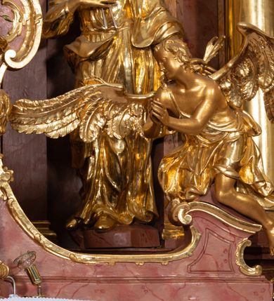 Zdjęcie nr 44: Nastawa ołtarzowa architektoniczna, jednokondygnacyjna ze zwieńczeniem, pięcioosiowa, ustawiona na wysokim cokole. Ołtarz wolnostojący, drewniany, sarkofagowy, wklęsło-wypukły, o zdwojonym froncie; mensa drewniana z marmurowym portatylem. Od frontu rocaille'owy kartusz ujęty fantazyjnymi płycinami oraz liśćmi. Na ołtarzu tabernakulum w formie sześcianu o wklęsłych bokach i wklęsło-wypukłym froncie; ujęte w narożach dwiema parami pilastrów o trzonach przechodzących w spływy wolutowe zdobione rocaille'm i różami. Pilastry podtrzymują falujący gzyms oraz fragmenty falistego, przerwanego, odwróconego przyczółka, przechodzącego w cokół, stanowiący tron wystawienia, na którym stoi krucyfiks. Na ściance frontowej obrotowa nisza, o wykroju stojącego prostokąta zamkniętego łukiem półkolistym, w opasce, zwieńczona kampanulami. W jej polu drzwiczki w formie stojącego prostokąta zamkniętego łukiem półkolistym w profilowanej ramie, z odlewanym przedstawieniem baranka leżącego na księdze z pieczęciami. Tabernakulum ujęte spływami przechodzącymi na krańcach we fragmenty wolutowego gzymsu, na których siedzą figury adorujących aniołów. Ponad tabernakulum fantazyjna ścianka tworząca tło dla tronu wystawienia z prześwitem otoczonym obłokami, z glorią promienistą, flankowana rocaille'owymi uszami. Cokół nastawy z wyodrębnionymi dwoma prostopadłościanami i dwoma konsolami, na dwóch skrajnych osiach bramki zamknięte wolutowymi szczytami tworzącymi cokoły dla figur, z przejściami w formie stojącego prostokąta zamkniętego łukiem odcinkowym nadwieszonym, z drzwiczkami. Cokół i drzwiczki dekorowane rocaille'm. Lico nastawy wklęsłe, osie wydzielone trzema parami pilastrów, na których tle stoją dwie pary kolumn o kapitelach kompozytowych. Podpory dźwigają pełne belkowanie, wyłamane na ich osi, przerwane nad polem środkowym, o gzymsie przechodzącym miejscami w rocaille'owe kartusze. Na osi środkowej wnęka z obrazem Matki Boskiej Wspomożenia Wiernych, w formie stojącego prostokąta zamkniętego łukiem odcinkowym nadwieszonym z uskokiem, ujęta profilowaną ramą, dekorowaną ponad łukiem płomienistym rocaille'm. Na pozostałych czterech osiach figury św. Barbary, św. Apolonii, św. Piotra i św. Pawła ustawione na rokokowych wspornikach. Trzony pilastrów i pola osi bocznych wypełnione rocaille'm, fryz dekorowany zwisami kwiatowymi. Zwieńczenie w formie zbliżonej do trapezu, zamknięte dwoma fragmentami gzymsu przechodzącego w woluty, flankowane wolutami spływającymi na belkowanie wewnętrznej pary kolumn, na których siedzą adorujące figury aniołów. W polu rzeźbiarska grupa Trójcy Świętej, pośród obłoków, w glorii promienistej, zwieńczona gołębicą Ducha Świętego w otoku z obłoków i uskrzydlonych główek anielskich, w glorii promienistej, flankowana przez dwa putta siedzące na gzymsie. Zwieńczenie po bokach obwiedzione rocaille'm, ujęte liśćmi palmowymi. Na belkowaniu, na osiach zewnętrznej pary kolumn wolutowe cokoły z rokokowymi wazonami. Struktura polichromowana na sposób imitujący marmoryzację w kolorze różowym i różowo-pomarańczowym, kolumny, profile i ornamentyka złocone, obłoki srebrzone. 

