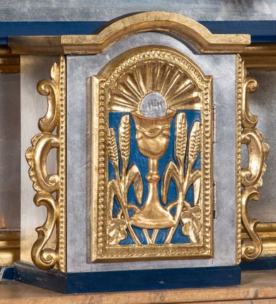 Zdjęcie nr 14: Nastawa architektoniczna, jednoosiowa, jednokondygnacyjna ze zwieńczeniem. Ołtarz sarkofagowy, wklęsło-wypukły, na cokole, z drewnianą mensą. Na ołtarzu tabernakulum w formie drewnianej skrzynki, obwiedzionej gzymsem i zwieńczonej cokołem z krzyżem. Drzwiczki w kształcie stojącego prostokąta zamkniętego łukiem odcinkowym nadwieszonym, w opasce, z płaskorzeźbionym przedstawieniem kielicha z hostią w glorii pomiędzy kłosami zbóż. Na ołtarzu dwie figury klęczących aniołów trzymających świeczniki. 
Nastawa ustawiona na cokole z wyodrębnionymi dwoma prostopadłościanami, ujęta parą kolumn podtrzymujących belkowanie, częściowo przerwane nad polem środkowym, o gzymsie wyłamanym na kształt łuku odcinkowego. Na belkowaniu fragmenty przerwanego, półkolistego przyczółka z siedzącą parą aniołków. W polu środkowym wnęka w formie stojącego prostokąta zamkniętego łukiem półkolistym nadwieszonym, z uskokiem, ujęta profilowaną ramą, z grupą rzeźbiarską Matki Boskiej Różańcowej ze św. Dominikiem i św. Katarzyną Sieneńską. Po zewnętrznej stronie kolumn ustawione figury św. Jacka i bł. Czesława. Wszystkie pola nastawy wypełnione stylizowanym rocaille&#039;m, uszy utworzone z rocaille&#039;u. Zwieńczenie w formie zbliżonej do trapezu, ujęte spływami wolutowymi, zamknięte dwoma fragmentami wolutowego gzymsu. W polu obraz w formie stojącego owalu, ujęty ramą, z przedstawieniem Dzieciątka Jezus. Zwieńczenie flankowane uszami utworzonymi z winnej latorośli. Całość zakończona rzeźbioną gołębicą Ducha Świętego w glorii promienistej. Struktura ołtarza polichromowana na srebrno, z niebieskimi elementami, złoconymi kolumnami, profilami i ornamentyką. 


