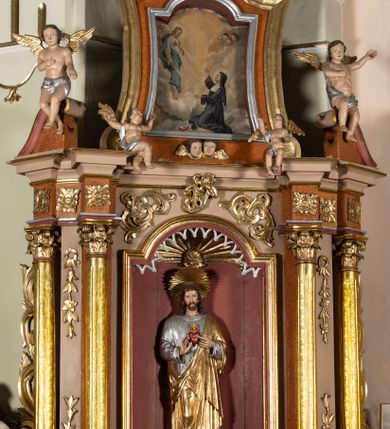 Zdjęcie nr 1: Nastawa architektoniczna, jednoosiowa, jednokondygnacyjna ze zwieńczeniem. Ołtarz drewniany, sarkofagowy, na cokole, z drewnianą mensą i kamiennym portatylem. Na froncie ołtarza namalowany owalny medalion ujęty wieńcem róż, z krzyżem, kotwicą i gorejącym sercem. Na ołtarzu tabernakulum w formie drewnianej skrzynki, ujętej parą kolumienek podtrzymujących imposty, z rocaille'owymi uszami. Drzwiczki w formie stojącego prostokąta zamkniętego łukiem półkolistym nadwieszonym. 
Nastawa ustawiona na cokole z wyłamanymi pod kątem czterema prostopadłościanami, dekorowanymi zwisami liściastymi. Retabulum ujęte dwiema parami kolumn, o trzonach dekorowanych rytą ornamentacją, z zewnętrzną parą ustawioną pod kątem, podtrzymującymi belkowanie, częściowo przerwane nad polem środkowym. Na belkowaniu fragmenty przerwanego, falistego przyczółka z siedzącymi puttami oraz para aniołków. W polu głównym wnęka w formie stojącego prostokąta zamkniętego łukiem odcinkowym nadwieszonym, ujęta profilowaną ramą, z figurą Najświętszego Serca Jezusa. Wnęka otoczona stylizowanymi ornamentami – akantem, rocaille'm i roślinnym, pomiędzy kolumnami roślinne zwisy, w partii fryzu rozety. Nastawa ujęta uszami utworzonymi ze stylizowanego ornamentu roślinnego. Zwieńczenie w formie zbliżonej do stojącego prostokąta, zamkniętego łukiem odcinkowym nadwieszonym, ujęte profilowaną ramą, przechodzącą po bokach w woluty,  dekorowane muszlą, ornamentem roślinnym i uskrzydlonymi główkami anielskimi. W polu wnęka w formie analogicznej do zwieńczenia, w profilowanej ramie, z obrazem wizji św. Małgorzaty Alacoque. Struktura polichromowana w kolorach bladoróżowym i pomarańczowym, kolumny, profile i ornamentyka złocone, detal srebrzony. 

