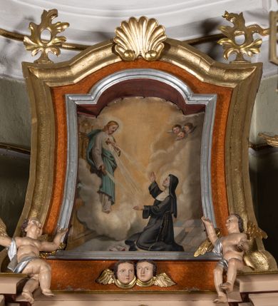 Zdjęcie nr 1: Obraz w formie stojącego prostokąta, zamkniętego łukiem odcinkowym nadwieszonym, o wklęsłych bokach. Święta Małgorzata ukazana w prawej, dolnej części obrazu, z profilu, w pozycji klęczącej, przed ołtarzem, z uniesioną głową i rozłożonymi na boki rękami. Ubrana jest w czarny habit, przepasany w talii, białą podwikę i czarny welon. Na ziemi leży otwarta księga. Przed nią, na tle ołtarza ukazany Chrystus unoszący się na tle obłoków. Zwrócony jest w trzech czwartych w lewo, z pochyloną głową, lewą ręką wskazuje na gorejące serce na jego piersi, prawą ma opuszczoną. Twarz ma szczupłą, okoloną jasną brodą i włosami. Ubrany jest w białą tunikę oraz jasnoniebieski płaszcz. Z jego ran na dłoniach i serca wydobywają się wiązki promieni skierowane w stronę świętej. Scena ukazana we wnętrzu z posadzką. W górnej części obrazu przedstawione obłoki i trzy uskrzydlone główki anielskie. 


