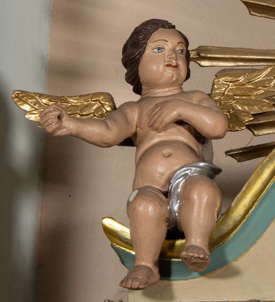 Zdjęcie nr 9: Nastawa architektoniczna, jednokondygnacyjna, jednoosiowa, ustawiona na cokole z wyodrębnionymi prostopadłościanami. Ołtarz drewniany, sarkofagowy, na cokole, z drewnianą mensą i kamiennym portatylem. Cokół nastawy dekorowany płycinami z akantem. Retabulum ujęte parą kolumn o skręconych trzonach i korynckich kapitelach, dźwigających pełne belkowanie, nad polem środkowym wyłamane na kształt łuku odcinkowego. Na belkowaniu fragmenty falistego, przerwanego przyczółka z siedzącymi puttami. Całe pole środkowe wypełnione wnęką w formie stojącego prostokąta zamkniętego łukiem półkolistym nadwieszonym, ujętą profilowaną ramą, z obrazem Matki Boskiej Wspomożenia Wiernych. Nastawa flankowana uszami utworzonymi z akantu i kratki regencyjnej. W miejscu zwieńczenia figura siedzącego na obłoku Chrystusa trzymającego krzyż, w glorii promienistej. Struktura polichromowana w kolorze beżowym, z jasnoniebieskimi i niebieskimi detalami, złoconymi kolumnami, profilami i ornamentyką oraz srebrzonymi detalami. 
