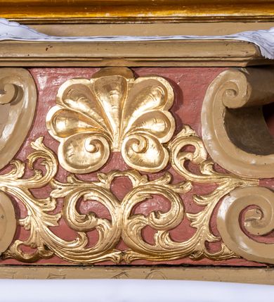 Zdjęcie nr 6: Nastawa architektoniczna, jednokondygnacyjna, jednoosiowa, ustawiona na cokole z wyodrębnionymi prostopadłościanami. Ołtarz drewniany, sarkofagowy, na cokole, z drewnianą mensą i kamiennym portatylem. Na ołtarzu ustawiony postument, ujęty spływami wolutowymi, dekorowany z przodu akantem i muszlą. Cokół nastawy dekorowany płycinami z uskrzydlonymi główkami anielskimi. Retabulum ujęte parą kolumn o skręconych trzonach i korynckich kapitelach, dźwigających niepełne belkowanie, częściowo przerwane nad polem środkowym, na którym gzyms wyłamany jest na kształt łuku odcinkowego. Na belkowaniu fragmenty falistego, przerwanego przyczółka z siedzącymi puttami. Całe pole środkowe wypełnione niszą w formie stojącego prostokąta zamkniętego łukiem półkolistym nadwieszonym, ujętą profilowaną ramą, z figurą św. Józefa z Dzieciątkiem. Nad niszą uskrzydlona główka anielska i dwie kiści winogron. Nastawa flankowana uszami utworzonymi z akantu i wstęgi regencyjnej. W miejscu zwieńczenia płaskorzeźbiona półpostać Boga Ojca pośród obłoków, w glorii promienistej. Struktura polichromowana w kolorze beżowym, z jasnoróżowymi detalami, srebrzonymi trzonami kolumn oraz złoconymi profilami i ornamentyką. 
