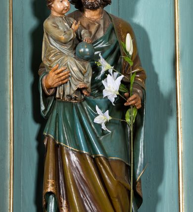 Zdjęcie nr 4: Nastawa architektoniczna, jednokondygnacyjna, jednoosiowa, ustawiona na cokole z wyodrębnionymi prostopadłościanami. Ołtarz drewniany, sarkofagowy, na cokole, z drewnianą mensą i kamiennym portatylem. Na ołtarzu ustawiony postument, ujęty spływami wolutowymi, dekorowany z przodu akantem i muszlą. Cokół nastawy dekorowany płycinami z uskrzydlonymi główkami anielskimi. Retabulum ujęte parą kolumn o skręconych trzonach i korynckich kapitelach, dźwigających niepełne belkowanie, częściowo przerwane nad polem środkowym, na którym gzyms wyłamany jest na kształt łuku odcinkowego. Na belkowaniu fragmenty falistego, przerwanego przyczółka z siedzącymi puttami. Całe pole środkowe wypełnione niszą w formie stojącego prostokąta zamkniętego łukiem półkolistym nadwieszonym, ujętą profilowaną ramą, z figurą św. Józefa z Dzieciątkiem. Nad niszą uskrzydlona główka anielska i dwie kiści winogron. Nastawa flankowana uszami utworzonymi z akantu i wstęgi regencyjnej. W miejscu zwieńczenia płaskorzeźbiona półpostać Boga Ojca pośród obłoków, w glorii promienistej. Struktura polichromowana w kolorze beżowym, z jasnoróżowymi detalami, srebrzonymi trzonami kolumn oraz złoconymi profilami i ornamentyką. 
