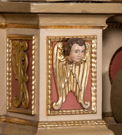 Zdjęcie nr 7: Nastawa architektoniczna, jednokondygnacyjna, jednoosiowa, ustawiona na cokole z wyodrębnionymi prostopadłościanami. Ołtarz drewniany, sarkofagowy, na cokole, z drewnianą mensą i kamiennym portatylem. Na ołtarzu ustawiony postument, ujęty spływami wolutowymi, dekorowany z przodu akantem i muszlą. Cokół nastawy dekorowany płycinami z uskrzydlonymi główkami anielskimi. Retabulum ujęte parą kolumn o skręconych trzonach i korynckich kapitelach, dźwigających niepełne belkowanie, częściowo przerwane nad polem środkowym, na którym gzyms wyłamany jest na kształt łuku odcinkowego. Na belkowaniu fragmenty falistego, przerwanego przyczółka z siedzącymi puttami. Całe pole środkowe wypełnione niszą w formie stojącego prostokąta zamkniętego łukiem półkolistym nadwieszonym, ujętą profilowaną ramą, z figurą św. Józefa z Dzieciątkiem. Nad niszą uskrzydlona główka anielska i dwie kiści winogron. Nastawa flankowana uszami utworzonymi z akantu i wstęgi regencyjnej. W miejscu zwieńczenia płaskorzeźbiona półpostać Boga Ojca pośród obłoków, w glorii promienistej. Struktura polichromowana w kolorze beżowym, z jasnoróżowymi detalami, srebrzonymi trzonami kolumn oraz złoconymi profilami i ornamentyką. 
