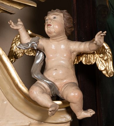 Zdjęcie nr 10: Nastawa architektoniczna, jednokondygnacyjna, jednoosiowa, ustawiona na cokole z wyodrębnionymi prostopadłościanami. Ołtarz drewniany, sarkofagowy, na cokole, z drewnianą mensą i kamiennym portatylem. Na ołtarzu ustawiony postument, ujęty spływami wolutowymi, dekorowany z przodu akantem i muszlą. Cokół nastawy dekorowany płycinami z uskrzydlonymi główkami anielskimi. Retabulum ujęte parą kolumn o skręconych trzonach i korynckich kapitelach, dźwigających niepełne belkowanie, częściowo przerwane nad polem środkowym, na którym gzyms wyłamany jest na kształt łuku odcinkowego. Na belkowaniu fragmenty falistego, przerwanego przyczółka z siedzącymi puttami. Całe pole środkowe wypełnione niszą w formie stojącego prostokąta zamkniętego łukiem półkolistym nadwieszonym, ujętą profilowaną ramą, z figurą św. Józefa z Dzieciątkiem. Nad niszą uskrzydlona główka anielska i dwie kiści winogron. Nastawa flankowana uszami utworzonymi z akantu i wstęgi regencyjnej. W miejscu zwieńczenia płaskorzeźbiona półpostać Boga Ojca pośród obłoków, w glorii promienistej. Struktura polichromowana w kolorze beżowym, z jasnoróżowymi detalami, srebrzonymi trzonami kolumn oraz złoconymi profilami i ornamentyką. 
