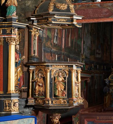 Zdjęcie nr 1: Rzeźba pełnoplastyczna przedstawiająca Chrystusa Salwatora na niskim, prostopadłościennym cokole o ściętych narożach. Chrystus ustawiony frontalnie, w kontrapoście z lewą nogą ugiętą w kolanie, prawą ręką błogosławi, a w lewej trzyma jabłko królewskie. Twarz podłużna, o delikatnie rzeźbionych rysach, okolona zarostem. Włosy jasnobrązowe, półdługie z przedziałkiem na środku głowy. Chrystus ubrany jest w długą, złotą suknię z podwiniętymi rękawami i zieloną podszewką oraz złoty płaszcz przewieszony przez lewe ramię z bordowym podbiciem. Polichromia naturalistyczna w partiach ciała, szaty i atrybuty złocone.