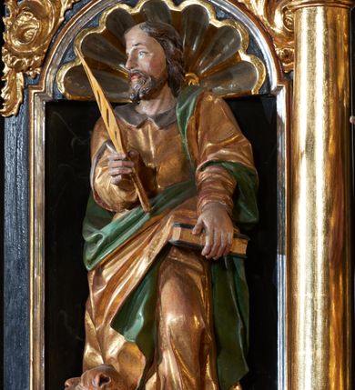 Zdjęcie nr 2: Rzeźba pełnoplastyczna, przedstawiająca św. Marka Ewangelistę. Święty ustawiony frontalnie, z głową zwróconą w prawo, z lewą nogą ugiętą w kolanie, księgą w lewej dłoni, którą wspiera o biodro oraz piórem w prawej dłoni.   Twarz pociągła z wysokim czołem, okolona zarostem, włosy średniej długości  z przedziałkiem na środku głowy. Ubrany jest w długą, złotą suknię z brązowym kołnierzem, przepasaną w talii i złoty płaszcz podbity na zielono, przewieszony przez lewe ramię i zawieszony na lewym boku. Przy prawej nodze lew, zwrócony w prawo. Polichromia naturalistyczna w partiach ciała, szaty złocone.