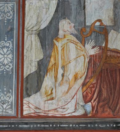 Zdjęcie nr 12: Prospekt organowy podwieszony przy północnej ścianie nawy, oparty na czterech filarach, dostępny z parapetu chóru. Balustrada drewniana z malowaną dekoracją; u spodu pas z ornamentem roślinnym; od frontu podzielona na trzynaście jednofiguralnych przedstawień w ramach, w formie wydłużonych, stojących prostokątów z przedstawieniami aniołów grających na instrumentach. Z boku na balustradzie dwie sceny w formie leżącego prostokąta ze św. Dawidem grającym na lirze i św. Cecylią grająca na organach, oddzielone pasem z dekoracją roślinną. 
Prospekt organowy architektoniczny, pięcioosiowy o bogatej dekoracji snycerskiej. Organy umieszczone na podstawie w kształcie leżącego prostokąta, dekorowanej dwiema płycinami z uszakami w narożach, z malowanymi przedstawieniami grających na instrumentach aniołów oraz z rzeźbionymi uskrzydlonymi główkami anielskimi w glorii pośrodku. Pod cokołem podwieszona dekoracja malarsko-rzeźbiarska nałożona na balustradę chóru. W centrum kompozycji malarskie przedstawienie trzech aniołów (jeden czyta księgę, a dwaj grają na instrumentach) w wieńcu laurowym. Poniżej, rzeźbiona uskrzydlona główka anielska, a całość ujęta ornamentem małżowinowo-chrząstkowym i zakończona u dołu szyszką. Prostokątna podstawa wspiera niski cokół, na którym ustawiona jest trójwieżyczkowa część główna. Środkowa, wyższa wieżyczka jest o przekroju półkolistym, a boczne kątowe o przekroju trójkątnym. Wieżyczki rozdzielają niższe prostokątne płyciny wypełnione piszczałkami. Pod wieżyczkami bocznymi podwieszone są złocone szyszki. Ażurowa dekoracja rzeźbiarska małżowino-chrząstkowa zdobi uszy organu, jest również umieszczona nad płycinami rozdzielającymi wieżyczki. Zwieńczenie tworzą na osiach bocznych strome szczyty, a pośrodku dwugłowy orzeł, na piersi którego w kartuszu w kształcie serca widnieją sygle „A[LBERTUS] B[INKOWICZ] / P[LEBANUS] O[RAVIENSIS]”. Piszczałki przysłaniają od góry ażurowe, rzeźbione firanki o motywie małżowinowo-chrząstkowym, a u dołu wąski pas dekoracji ornamentalnej z motywem silnie przestylizowanych lilii. Organy polichromowane na czarno, profilowania w kolorze czerwonym, zielonym i pomarańczowym, ornamentyka złocona i srebrzona. 



