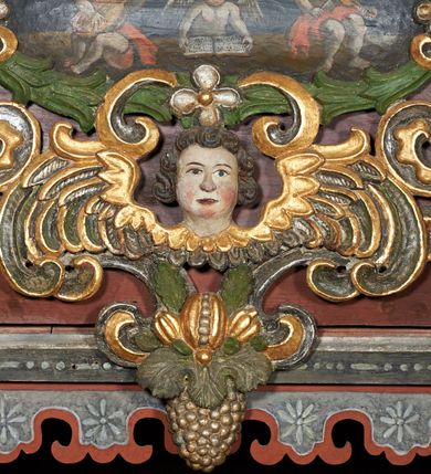 Zdjęcie nr 26: Prospekt organowy podwieszony przy północnej ścianie nawy, oparty na czterech filarach, dostępny z parapetu chóru. Balustrada drewniana z malowaną dekoracją; u spodu pas z ornamentem roślinnym; od frontu podzielona na trzynaście jednofiguralnych przedstawień w ramach, w formie wydłużonych, stojących prostokątów z przedstawieniami aniołów grających na instrumentach. Z boku na balustradzie dwie sceny w formie leżącego prostokąta ze św. Dawidem grającym na lirze i św. Cecylią grająca na organach, oddzielone pasem z dekoracją roślinną. 
Prospekt organowy architektoniczny, pięcioosiowy o bogatej dekoracji snycerskiej. Organy umieszczone na podstawie w kształcie leżącego prostokąta, dekorowanej dwiema płycinami z uszakami w narożach, z malowanymi przedstawieniami grających na instrumentach aniołów oraz z rzeźbionymi uskrzydlonymi główkami anielskimi w glorii pośrodku. Pod cokołem podwieszona dekoracja malarsko-rzeźbiarska nałożona na balustradę chóru. W centrum kompozycji malarskie przedstawienie trzech aniołów (jeden czyta księgę, a dwaj grają na instrumentach) w wieńcu laurowym. Poniżej, rzeźbiona uskrzydlona główka anielska, a całość ujęta ornamentem małżowinowo-chrząstkowym i zakończona u dołu szyszką. Prostokątna podstawa wspiera niski cokół, na którym ustawiona jest trójwieżyczkowa część główna. Środkowa, wyższa wieżyczka jest o przekroju półkolistym, a boczne kątowe o przekroju trójkątnym. Wieżyczki rozdzielają niższe prostokątne płyciny wypełnione piszczałkami. Pod wieżyczkami bocznymi podwieszone są złocone szyszki. Ażurowa dekoracja rzeźbiarska małżowino-chrząstkowa zdobi uszy organu, jest również umieszczona nad płycinami rozdzielającymi wieżyczki. Zwieńczenie tworzą na osiach bocznych strome szczyty, a pośrodku dwugłowy orzeł, na piersi którego w kartuszu w kształcie serca widnieją sygle „A[LBERTUS] B[INKOWICZ] / P[LEBANUS] O[RAVIENSIS]”. Piszczałki przysłaniają od góry ażurowe, rzeźbione firanki o motywie małżowinowo-chrząstkowym, a u dołu wąski pas dekoracji ornamentalnej z motywem silnie przestylizowanych lilii. Organy polichromowane na czarno, profilowania w kolorze czerwonym, zielonym i pomarańczowym, ornamentyka złocona i srebrzona. 



