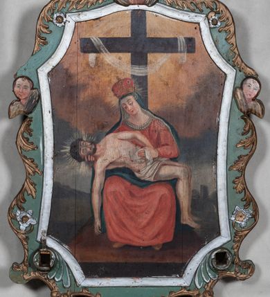 Zdjęcie nr 2: Feretron dwustronny, ustawiony na niskiej profilowanej podstawie z obrazami przedstawiającymi Pietę oraz Eliasza. Płótna ujęte są ramą w kształcie zbliżonym do stojącego prostokąta o fantazyjnym przebiegu. Rama od zewnątrz dekorowana wicią stylizowanego akantu, a po bokach i w zwieńczeniu uskrzydlonymi główkami anielskimi a także czterema kwiatkami. W dolnej części ramy otwory na drążki do noszenia i dwie stylizowane muszle. Po jednej stronie feretronu obraz przedstawiający Piętę. W centrum kompozycji Matka Boża ze zmarłym Chrystusem złożonym na jej kolanach, ukazani na wysokim prostopadłościennym podeście na tle krzyża z przewieszoną przez ramiona białą szarfą. Maria ustawiona frontalnie w pozycji siedzącej, z głową lekko skierowaną w prawo i w dół. Ubrana jest w długą, czerwoną suknię zdobioną perełkowaniem u szyi, granatowy płaszcz założony na głowę i koronę zamkniętą. Twarz owalna z  długim nosem, małymi i drobnymi ustami oraz przymkniętymi oczami ze wzrokiem skierowanym na Chrystusa; po jej policzkach spływają łzy. Chrystus widoczny z prawego półprofilu z prawą ręką opadającą bezwładnie w dół, lewą złożoną na biodrach. Twarz trójkątna z zamkniętymi oczami i otwartymi ustami, okolona krótką brodą i ciemnymi włosami. Chrystus ubrany jest w białe perizonium, na głowie ma założoną koronę cierniową. Całość ukazana jest na tle ciemnego krajobrazu, w górnej części ugrowe pochmurne niebo, wokół głów postaci promieniste nimby. Po drugiej stronie feretronu obraz przedstawiający proroka Eliasza w pustelni. W centrum kompozycji siedzi Eliasz z zakonnikiem przy kwadratowym stoliku na tle egzotycznego krajobrazu. Obaj mężczyźni o podobnych rysach twarzy z długimi i siwymi brodami. Eliasz ubrany jest w suknię ze skóry koźlęcia, a zakonnik w strój karmelity. Pomiędzy nimi stoi wysoka palma, nad którą wznosi się nadlatujący kruk z chlebem w dziobie. Na stoliku leżą różaniec i miska, u dołu obrazu tryska małe źródełko. Kolorystyka przytłumiona, brunatno-błękitna, o pojedynczych, intensywnych plamach barwnych.