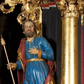 Zdjęcie nr 1: Rzeźba pełna, przedstawiająca św. Jakuba Większego. Święty delikatnie zwrócony w prawo, z prawą nogą ugiętą w kolanie, lewą ręką ma złożoną na piersi, w prawej trzyma kij pielgrzyma. Twarz podłużna z dużymi oczami i długim nosem, okolona bujną, brązową i krótką brodą oraz krótkimi włosami. Święty ubrany jest w niebieską suknię, obficie drapowaną u dołu, przewiązaną w talii złotym paskiem oraz złocony płaszcz z czerwoną podszewką, odsłaniający lewe ramię; na stopach ma założone brązowe buty. Polichromia w odsłoniętych partiach ciała naturalistyczna, płaszcz i laska złocone.