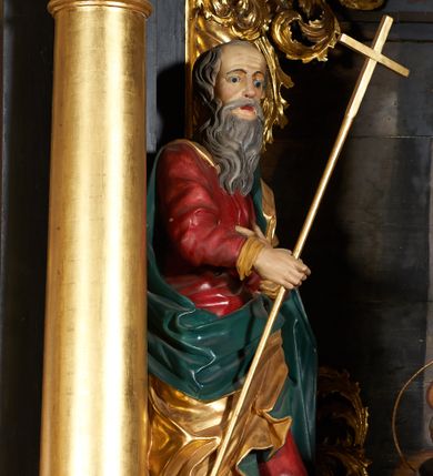 Zdjęcie nr 1: Rzeźba pełna, przedstawiająca św. Filipa. Figura zwrócona delikatnie w lewo, sylwetka o lekko skręconym tułowiu z lewą nogą ugiętą w kolanie, w prawej dłoni trzyma krzyż na długim drzewcu, lewą składa na piersi. Twarz o rysach starszego mężczyzny z długą, siwą i bujną brodą, czoło wysokie z zakolami i krótkimi, siwymi włosami. Święty ubrany jest w długą i czerwoną suknię, złocony płaszcz z zieloną podszewką, odsłaniający prawe ramię i przerzucony przez lewe przedramię; na stopach ma założone brązowe buty. Polichromia w odsłoniętych partiach ciała naturalistyczna, płaszcz i krzyż złocone.

