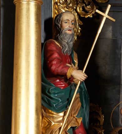 Zdjęcie nr 1: Rzeźba pełna, przedstawiająca św. Filipa. Figura zwrócona delikatnie w lewo, sylwetka o lekko skręconym tułowiu z lewą nogą ugiętą w kolanie, w prawej dłoni trzyma krzyż na długim drzewcu, lewą składa na piersi. Twarz o rysach starszego mężczyzny z długą, siwą i bujną brodą, czoło wysokie z zakolami i krótkimi, siwymi włosami. Święty ubrany jest w długą i czerwoną suknię, złocony płaszcz z zieloną podszewką, odsłaniający prawe ramię i przerzucony przez lewe przedramię; na stopach ma założone brązowe buty. Polichromia w odsłoniętych partiach ciała naturalistyczna, płaszcz i krzyż złocone.

