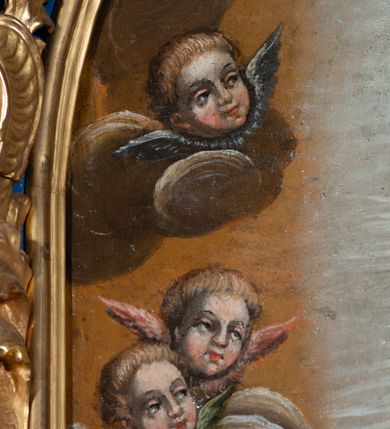 Zdjęcie nr 10: Obraz w formie stojącego prostokąta zamkniętego półkoliście z przedstawieniem Matki Boskiej Niepokalanie Poczętej. Na jasnobrązowym tle nieba ukazana Maria otoczona jasną poświatą, przedstawiona w całej postaci, stojąca na półksiężycu i skłębionych obłokach. Matka Boska wyobrażona frontalnie z głową lekko pochyloną, zwróconą w prawą stronę, z rękami złożonymi na piersi. Twarz owalna, o dziewczęcych rysach i jasnej karnacji z zaróżowionymi policzkami, łuki brwiowe regularne, oczy przymknięte, nos prosty, usta pełne i czerwone. Maria ubrana jest w długą, białą suknię przewiązaną w pasie czerwoną szarfą, ciemnobłękitny płaszcz dekorowany złotym ornamentem kwiatowym oraz biały welon na głowie. Po bokach Matki Boskiej ukazane są uskrzydlone główki anielskie na obłokach, poniżej dwa uskrzydlone, nagie putta trzymające gałązkę lilii i zwierciadło. U dołu kompozycji sumaryczny pejzaż ze wzgórzami i ruinami. Kolorystyka ciepła, z zastosowanymi zimnymi plamami barwnymi, światłocieniem i laserunkami. Rama złocona, drewniana, profilowana, dekorowana ornamentem akantowym na niebieskim tle. 