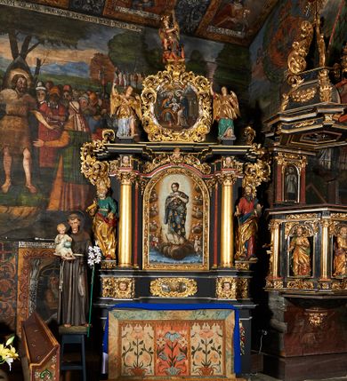 Zdjęcie nr 1: Nastawa architektoniczna, jednoosiowa, jednokondygnacyjna ze zwieńczeniem. Ołtarz prostopadłościenny, drewniany, mensa drewniana z kamiennym portatylem. Antepedium drewniane z malowaną dekoracją w postaci ramy i trzech pól z dekoracją roślinną i ptakami; zwieńczone od góry lambrekinem. W predelli obraz Zwiastowania Najświętszej Marii Pannie. Nastawa ołtarzowa na podwójnym cokole, ujęta zwielokrotnionymi pilastrami, na tle których kolumny o kapitelach kompozytowych, dźwigające belkowanie wyłamane na ich osi o silnie wysuniętym gzymsie. Pole środkowe w kształcie stojącego prostokąta zakończonego łukiem półkolistymi, w środku obraz Matki Boskiej Niepokalanie Poczętej. Po bokach figury: św. Piotra po lewej i św. Pawła po prawej. Zwieńczenie w formie okrągłego pola obrazowego obwiedzionego srebrną ramą imitującą wieniec laurowy oraz ażurowym, suchym akantem. W polu obraz z przedstawieniem Świętej Rodziny; na belkowaniu, na osi kolumn na postumentach figury aniołów. Dekorację ornamentalną nastawy stanowią w części dolnej cokołu girlandy, w części cokołowej zasadniczej nastawy liście akantu oraz uskrzydlone główki anielskie na tle akantu; w partii fryzu liście akantu, nad kolumnami uskrzydlone główki anielskie. Kondygnacja ujęta uszami utworzonymi z ażurowego akantu.  Zwieńczenie zakończone cokołem z figurą św. Michała Archanioła. Polichromia całości struktury ołtarza w kolorze czarnym, pilastry flankujące pole środkowe marmoryzowane w odcieniu czerwonym, profilowania i detal architektoniczny pozłacane i posrebrzane.