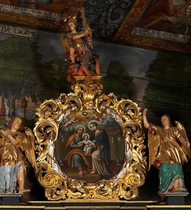 Zdjęcie nr 9: Nastawa architektoniczna, jednoosiowa, jednokondygnacyjna ze zwieńczeniem. Ołtarz prostopadłościenny, drewniany, mensa drewniana z kamiennym portatylem. Antepedium drewniane z malowaną dekoracją w postaci ramy i trzech pól z dekoracją roślinną i ptakami; zwieńczone od góry lambrekinem. W predelli obraz Zwiastowania Najświętszej Marii Pannie. Nastawa ołtarzowa na podwójnym cokole, ujęta zwielokrotnionymi pilastrami, na tle których kolumny o kapitelach kompozytowych, dźwigające belkowanie wyłamane na ich osi o silnie wysuniętym gzymsie. Pole środkowe w kształcie stojącego prostokąta zakończonego łukiem półkolistymi, w środku obraz Matki Boskiej Niepokalanie Poczętej. Po bokach figury: św. Piotra po lewej i św. Pawła po prawej. Zwieńczenie w formie okrągłego pola obrazowego obwiedzionego srebrną ramą imitującą wieniec laurowy oraz ażurowym, suchym akantem. W polu obraz z przedstawieniem Świętej Rodziny; na belkowaniu, na osi kolumn na postumentach figury aniołów. Dekorację ornamentalną nastawy stanowią w części dolnej cokołu girlandy, w części cokołowej zasadniczej nastawy liście akantu oraz uskrzydlone główki anielskie na tle akantu; w partii fryzu liście akantu, nad kolumnami uskrzydlone główki anielskie. Kondygnacja ujęta uszami utworzonymi z ażurowego akantu.  Zwieńczenie zakończone cokołem z figurą św. Michała Archanioła. Polichromia całości struktury ołtarza w kolorze czarnym, pilastry flankujące pole środkowe marmoryzowane w odcieniu czerwonym, profilowania i detal architektoniczny pozłacane i posrebrzane.