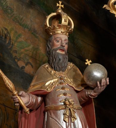 Zdjęcie nr 1: Rzeźba ścięta z tyłu, przedstawiająca św. Stefana. Święty ukazany frontalnie w postawie stojącej z jabłkiem królewskim w prawej dłoni i berłem w lewej. Twarz podłużna o dużych oczach, lekko rozchylonych ustach, okolona długą, bujną, czarną brodą. Święty ubrany jest w strój szlachecki, składający się z wysokich butów, srebrzonego kontusza przepasanego w partii bioder, zapinanego na guzy oraz przerzuconego przez ramiona, spiętego na piersi złotego płaszcza z czerwoną podszewką, ozdobionego kaboszonami i rautami na lamówce. Polichromia naturalistyczna w partiach ciała, szaty i atrybuty złocone i srebrzone.