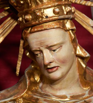 Zdjęcie nr 4: Siedząca figura Matki Boskiej zwrócona trzy czwarte w prawo, z pochyloną głową, podtrzymuje leżące na jej kolanach ciało martwego Chrystusa. Lewą ręką obejmuje jego ramię, prawą podtrzymuje głowę. Twarz Matki Boskiej szczupła o starczych rysach, oczy skierowane w dół, długi nos, rozchylone usta. Postać ubrana w złotą suknię o dekoracyjnie potraktowanych rękawach, silnie przylegającą do ciała w dolnej partii oraz obficie drapowany płaszcz przykrywający głowę i opadający na plecy. Na głowie dekoracyjna korona otoczona wokół niej promienistą glorią. Ciało Chrystusa opada bezwładnie, lewa ręka ugięta, prawa układa się wzdłuż boku Marii. Twarz ascetyczna, o wyraźnych rysach, zapadłych policzkach, oczy na wpół przymknięte, usta rozchylone; okolona zarostem. Włosy długie w postaci bujnych loków, opadają na ramiona; na głowie korona cierniowa w glorii. Ciało wychudłe, plastycznie kształtowane o wyrazistej anatomii z zaznaczonymi śladami męki, obficie broczącymi krwią. Przez biodra przepasane krótkie perizonium.
Polichromia naturalistyczna w partiach ciała, szaty złocone.