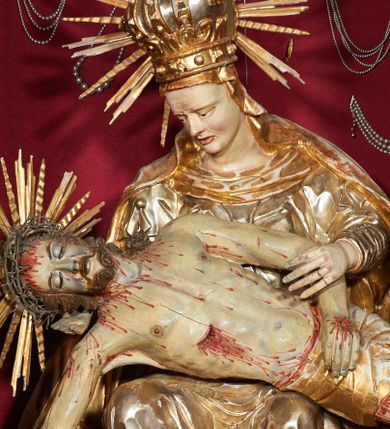 Zdjęcie nr 1: Siedząca figura Matki Boskiej zwrócona trzy czwarte w prawo, z pochyloną głową, podtrzymuje leżące na jej kolanach ciało martwego Chrystusa. Lewą ręką obejmuje jego ramię, prawą podtrzymuje głowę. Twarz Matki Boskiej szczupła o starczych rysach, oczy skierowane w dół, długi nos, rozchylone usta. Postać ubrana w złotą suknię o dekoracyjnie potraktowanych rękawach, silnie przylegającą do ciała w dolnej partii oraz obficie drapowany płaszcz przykrywający głowę i opadający na plecy. Na głowie dekoracyjna korona otoczona wokół niej promienistą glorią. Ciało Chrystusa opada bezwładnie, lewa ręka ugięta, prawa układa się wzdłuż boku Marii. Twarz ascetyczna, o wyraźnych rysach, zapadłych policzkach, oczy na wpół przymknięte, usta rozchylone; okolona zarostem. Włosy długie w postaci bujnych loków, opadają na ramiona; na głowie korona cierniowa w glorii. Ciało wychudłe, plastycznie kształtowane o wyrazistej anatomii z zaznaczonymi śladami męki, obficie broczącymi krwią. Przez biodra przepasane krótkie perizonium.
Polichromia naturalistyczna w partiach ciała, szaty złocone.