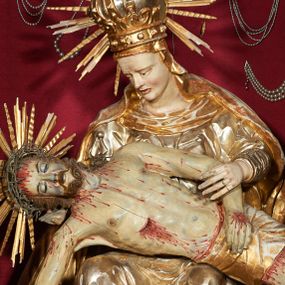 Zdjęcie nr 1: Siedząca figura Matki Boskiej zwrócona trzy czwarte w prawo, z pochyloną głową, podtrzymuje leżące na jej kolanach ciało martwego Chrystusa. Lewą ręką obejmuje jego ramię, prawą podtrzymuje głowę. Twarz Matki Boskiej szczupła o starczych rysach, oczy skierowane w dół, długi nos, rozchylone usta. Postać ubrana w złotą suknię o dekoracyjnie potraktowanych rękawach, silnie przylegającą do ciała w dolnej partii oraz obficie drapowany płaszcz przykrywający głowę i opadający na plecy. Na głowie dekoracyjna korona otoczona wokół niej promienistą glorią. Ciało Chrystusa opada bezwładnie, lewa ręka ugięta, prawa układa się wzdłuż boku Marii. Twarz ascetyczna, o wyraźnych rysach, zapadłych policzkach, oczy na wpół przymknięte, usta rozchylone; okolona zarostem. Włosy długie w postaci bujnych loków, opadają na ramiona; na głowie korona cierniowa w glorii. Ciało wychudłe, plastycznie kształtowane o wyrazistej anatomii z zaznaczonymi śladami męki, obficie broczącymi krwią. Przez biodra przepasane krótkie perizonium.
Polichromia naturalistyczna w partiach ciała, szaty złocone.