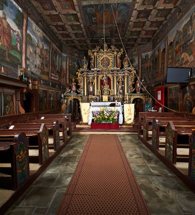 Zdjęcie nr 26: Nastawa ołtarzowa architektoniczna, trójosiowa, dwukondygnacyjna na cokole z bramkami. Ołtarz prostopadłościenny, drewniany. Mensa drewniana z kamiennym portatylem. Antepedium w formie leżącego prostokąta z przedstawieniem pelikana karmiącego młode. Całość ujęta bujną dekoracją roślinną z kwiatami ukazaną na złotym tle. U dołu napis: „A(NNO) D(OMINI) M C M X X I V”. Tabernakulum nowe w formie prostopadłościennej skrzynki. Na ściance frontowej drzwiczki w kształcie stojącego prostokąta zamkniętego łukiem nadwieszonym. W polu płaskorzeźbiony kielich z hostią oraz winna latorośl, powyżej dwa anioły. Nastawa ustawiona na zdwojonym cokole. Cokół dekorowany akantem mięsistym, owocowymi girlandami oraz uskrzydlonymi główkami anielskimi  na osi kolumn.

Osie pierwszej kondygnacji retabulum wydzielone czterema kolumnami o kapitelach korynckich ustawionymi na tle pilastrów, dźwigającymi pełne belkowanie zamknięte wydatnym gzymsem, wyłamane w partii podpór; nad polem środkowym przyjmujące formę łuku odcinkowego; na osi zewnętrznej pary podpór przerwany, odwrócony przyczółek. W polu środkowym rama w formie stojącego prostokąta zamkniętego łukiem półkolistym, w której umieszczona jest rzeźbiona Pieta. Na zasuwie obraz św. Jana Chrzciciela. Rama zdobiona ornamentem roślinnym, w przyłuczach uskrzydlone główki anielskie. Powyżej medalion z rzeźbioną głową św. Jana Chrzciciela na tacy w ramie z mięsistego, ażurowego akantu. W osiach bocznych płytkie nisze z figurami św. Wojciecha po lewej stronie i św. Stanisława po prawej. Nisze w osiach bocznych zamknięte konchą, ponad którą wstęga z koszem i owocami. Fryz dekorowany girlandami z tkaniny i owoców oraz uskrzydlonymi główkami anielskimi na osi podpór. Kondygnacja ujęta bujnymi uszami z ażurowego, suchego akantu. 

Druga kondygnacja szerokości osi środkowej, ujęta parą kolumn o kapitelach korynckich dźwigających pełne belkowanie z wydatnym gzymsem wyłamane na ich osi oraz przerwany przyczółek. W polu środkowym rama w formie stojącego prostokąta o ściętych narożach z obrazem Matki Boskiej. Kondygnacja flankowana przez figury św. Barbary po lewej stronie i św. Katarzyny po prawej. Z kolei na osi skrajnych kolumn, za przyczółkami ustawiona jest druga para dwóch świętych prawdopodobnie węgierskich. Fryz dekorowany akantem oraz uskrzydlonymi główkami anielskimi na osi podpór. Kondygnacja ujęta ażurowym suchym akantem. Na szczycie figura tronującej Matki Boskiej Królowej Niebios, stojącej na półksiężycu w glorii oraz dwa putta.
Bramki z przejściem w formie stojącego prostokąta zamkniętego łukiem półkolistym, ujęte pilastrami dźwigającymi niepełne belkowanie zamknięte silnie wystającym gzymsem i falistym, przerwanym przyczółkiem z siedzącymi puttami. Ponad bramkami na cokołach ustawione są figury św. Stefana po lewej stronie i św. Władysława po prawej. Drzwiczki bramek z malowanymi przedstawieniami św. Piotra po lewej stronie i św. Pawła po prawej. W przyłuczach i fryzie akant.
Nastawa marmoryzowana  w kolorze ciemnej zieleni ze złoconymi oraz srebrzonymi detalami architektonicznymi i ornamentyką. Na odwrociu ołtarza znajduje się malowidło przedstawiające św. Marię Magdalenę.