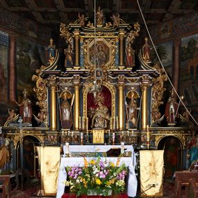 Zdjęcie nr 1: Nastawa ołtarzowa architektoniczna, trójosiowa, dwukondygnacyjna na cokole z bramkami. Ołtarz prostopadłościenny, drewniany. Mensa drewniana z kamiennym portatylem. Antepedium w formie leżącego prostokąta z przedstawieniem pelikana karmiącego młode. Całość ujęta bujną dekoracją roślinną z kwiatami ukazaną na złotym tle. U dołu napis: „A(NNO) D(OMINI) M C M X X I V”. Tabernakulum nowe w formie prostopadłościennej skrzynki. Na ściance frontowej drzwiczki w kształcie stojącego prostokąta zamkniętego łukiem nadwieszonym. W polu płaskorzeźbiony kielich z hostią oraz winna latorośl, powyżej dwa anioły. Nastawa ustawiona na zdwojonym cokole. Cokół dekorowany akantem mięsistym, owocowymi girlandami oraz uskrzydlonymi główkami anielskimi  na osi kolumn.

Osie pierwszej kondygnacji retabulum wydzielone czterema kolumnami o kapitelach korynckich ustawionymi na tle pilastrów, dźwigającymi pełne belkowanie zamknięte wydatnym gzymsem, wyłamane w partii podpór; nad polem środkowym przyjmujące formę łuku odcinkowego; na osi zewnętrznej pary podpór przerwany, odwrócony przyczółek. W polu środkowym rama w formie stojącego prostokąta zamkniętego łukiem półkolistym, w której umieszczona jest rzeźbiona Pieta. Na zasuwie obraz św. Jana Chrzciciela. Rama zdobiona ornamentem roślinnym, w przyłuczach uskrzydlone główki anielskie. Powyżej medalion z rzeźbioną głową św. Jana Chrzciciela na tacy w ramie z mięsistego, ażurowego akantu. W osiach bocznych płytkie nisze z figurami św. Wojciecha po lewej stronie i św. Stanisława po prawej. Nisze w osiach bocznych zamknięte konchą, ponad którą wstęga z koszem i owocami. Fryz dekorowany girlandami z tkaniny i owoców oraz uskrzydlonymi główkami anielskimi na osi podpór. Kondygnacja ujęta bujnymi uszami z ażurowego, suchego akantu. 

Druga kondygnacja szerokości osi środkowej, ujęta parą kolumn o kapitelach korynckich dźwigających pełne belkowanie z wydatnym gzymsem wyłamane na ich osi oraz przerwany przyczółek. W polu środkowym rama w formie stojącego prostokąta o ściętych narożach z obrazem Matki Boskiej. Kondygnacja flankowana przez figury św. Barbary po lewej stronie i św. Katarzyny po prawej. Z kolei na osi skrajnych kolumn, za przyczółkami ustawiona jest druga para dwóch świętych prawdopodobnie węgierskich. Fryz dekorowany akantem oraz uskrzydlonymi główkami anielskimi na osi podpór. Kondygnacja ujęta ażurowym suchym akantem. Na szczycie figura tronującej Matki Boskiej Królowej Niebios, stojącej na półksiężycu w glorii oraz dwa putta.
Bramki z przejściem w formie stojącego prostokąta zamkniętego łukiem półkolistym, ujęte pilastrami dźwigającymi niepełne belkowanie zamknięte silnie wystającym gzymsem i falistym, przerwanym przyczółkiem z siedzącymi puttami. Ponad bramkami na cokołach ustawione są figury św. Stefana po lewej stronie i św. Władysława po prawej. Drzwiczki bramek z malowanymi przedstawieniami św. Piotra po lewej stronie i św. Pawła po prawej. W przyłuczach i fryzie akant.
Nastawa marmoryzowana  w kolorze ciemnej zieleni ze złoconymi oraz srebrzonymi detalami architektonicznymi i ornamentyką. Na odwrociu ołtarza znajduje się malowidło przedstawiające św. Marię Magdalenę.