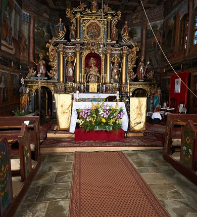 Zdjęcie nr 2: Nastawa ołtarzowa architektoniczna, trójosiowa, dwukondygnacyjna na cokole z bramkami. Ołtarz prostopadłościenny, drewniany. Mensa drewniana z kamiennym portatylem. Antepedium w formie leżącego prostokąta z przedstawieniem pelikana karmiącego młode. Całość ujęta bujną dekoracją roślinną z kwiatami ukazaną na złotym tle. U dołu napis: „A(NNO) D(OMINI) M C M X X I V”. Tabernakulum nowe w formie prostopadłościennej skrzynki. Na ściance frontowej drzwiczki w kształcie stojącego prostokąta zamkniętego łukiem nadwieszonym. W polu płaskorzeźbiony kielich z hostią oraz winna latorośl, powyżej dwa anioły. Nastawa ustawiona na zdwojonym cokole. Cokół dekorowany akantem mięsistym, owocowymi girlandami oraz uskrzydlonymi główkami anielskimi  na osi kolumn.

Osie pierwszej kondygnacji retabulum wydzielone czterema kolumnami o kapitelach korynckich ustawionymi na tle pilastrów, dźwigającymi pełne belkowanie zamknięte wydatnym gzymsem, wyłamane w partii podpór; nad polem środkowym przyjmujące formę łuku odcinkowego; na osi zewnętrznej pary podpór przerwany, odwrócony przyczółek. W polu środkowym rama w formie stojącego prostokąta zamkniętego łukiem półkolistym, w której umieszczona jest rzeźbiona Pieta. Na zasuwie obraz św. Jana Chrzciciela. Rama zdobiona ornamentem roślinnym, w przyłuczach uskrzydlone główki anielskie. Powyżej medalion z rzeźbioną głową św. Jana Chrzciciela na tacy w ramie z mięsistego, ażurowego akantu. W osiach bocznych płytkie nisze z figurami św. Wojciecha po lewej stronie i św. Stanisława po prawej. Nisze w osiach bocznych zamknięte konchą, ponad którą wstęga z koszem i owocami. Fryz dekorowany girlandami z tkaniny i owoców oraz uskrzydlonymi główkami anielskimi na osi podpór. Kondygnacja ujęta bujnymi uszami z ażurowego, suchego akantu. 

Druga kondygnacja szerokości osi środkowej, ujęta parą kolumn o kapitelach korynckich dźwigających pełne belkowanie z wydatnym gzymsem wyłamane na ich osi oraz przerwany przyczółek. W polu środkowym rama w formie stojącego prostokąta o ściętych narożach z obrazem Matki Boskiej. Kondygnacja flankowana przez figury św. Barbary po lewej stronie i św. Katarzyny po prawej. Z kolei na osi skrajnych kolumn, za przyczółkami ustawiona jest druga para dwóch świętych prawdopodobnie węgierskich. Fryz dekorowany akantem oraz uskrzydlonymi główkami anielskimi na osi podpór. Kondygnacja ujęta ażurowym suchym akantem. Na szczycie figura tronującej Matki Boskiej Królowej Niebios, stojącej na półksiężycu w glorii oraz dwa putta.
Bramki z przejściem w formie stojącego prostokąta zamkniętego łukiem półkolistym, ujęte pilastrami dźwigającymi niepełne belkowanie zamknięte silnie wystającym gzymsem i falistym, przerwanym przyczółkiem z siedzącymi puttami. Ponad bramkami na cokołach ustawione są figury św. Stefana po lewej stronie i św. Władysława po prawej. Drzwiczki bramek z malowanymi przedstawieniami św. Piotra po lewej stronie i św. Pawła po prawej. W przyłuczach i fryzie akant.
Nastawa marmoryzowana  w kolorze ciemnej zieleni ze złoconymi oraz srebrzonymi detalami architektonicznymi i ornamentyką. Na odwrociu ołtarza znajduje się malowidło przedstawiające św. Marię Magdalenę.