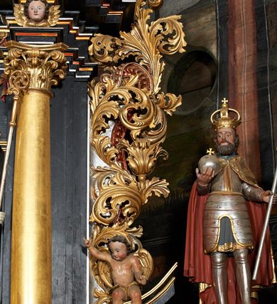 Zdjęcie nr 15: Nastawa ołtarzowa architektoniczna, trójosiowa, dwukondygnacyjna na cokole z bramkami. Ołtarz prostopadłościenny, drewniany. Mensa drewniana z kamiennym portatylem. Antepedium w formie leżącego prostokąta z przedstawieniem pelikana karmiącego młode. Całość ujęta bujną dekoracją roślinną z kwiatami ukazaną na złotym tle. U dołu napis: „A(NNO) D(OMINI) M C M X X I V”. Tabernakulum nowe w formie prostopadłościennej skrzynki. Na ściance frontowej drzwiczki w kształcie stojącego prostokąta zamkniętego łukiem nadwieszonym. W polu płaskorzeźbiony kielich z hostią oraz winna latorośl, powyżej dwa anioły. Nastawa ustawiona na zdwojonym cokole. Cokół dekorowany akantem mięsistym, owocowymi girlandami oraz uskrzydlonymi główkami anielskimi  na osi kolumn.

Osie pierwszej kondygnacji retabulum wydzielone czterema kolumnami o kapitelach korynckich ustawionymi na tle pilastrów, dźwigającymi pełne belkowanie zamknięte wydatnym gzymsem, wyłamane w partii podpór; nad polem środkowym przyjmujące formę łuku odcinkowego; na osi zewnętrznej pary podpór przerwany, odwrócony przyczółek. W polu środkowym rama w formie stojącego prostokąta zamkniętego łukiem półkolistym, w której umieszczona jest rzeźbiona Pieta. Na zasuwie obraz św. Jana Chrzciciela. Rama zdobiona ornamentem roślinnym, w przyłuczach uskrzydlone główki anielskie. Powyżej medalion z rzeźbioną głową św. Jana Chrzciciela na tacy w ramie z mięsistego, ażurowego akantu. W osiach bocznych płytkie nisze z figurami św. Wojciecha po lewej stronie i św. Stanisława po prawej. Nisze w osiach bocznych zamknięte konchą, ponad którą wstęga z koszem i owocami. Fryz dekorowany girlandami z tkaniny i owoców oraz uskrzydlonymi główkami anielskimi na osi podpór. Kondygnacja ujęta bujnymi uszami z ażurowego, suchego akantu. 

Druga kondygnacja szerokości osi środkowej, ujęta parą kolumn o kapitelach korynckich dźwigających pełne belkowanie z wydatnym gzymsem wyłamane na ich osi oraz przerwany przyczółek. W polu środkowym rama w formie stojącego prostokąta o ściętych narożach z obrazem Matki Boskiej. Kondygnacja flankowana przez figury św. Barbary po lewej stronie i św. Katarzyny po prawej. Z kolei na osi skrajnych kolumn, za przyczółkami ustawiona jest druga para dwóch świętych prawdopodobnie węgierskich. Fryz dekorowany akantem oraz uskrzydlonymi główkami anielskimi na osi podpór. Kondygnacja ujęta ażurowym suchym akantem. Na szczycie figura tronującej Matki Boskiej Królowej Niebios, stojącej na półksiężycu w glorii oraz dwa putta.
Bramki z przejściem w formie stojącego prostokąta zamkniętego łukiem półkolistym, ujęte pilastrami dźwigającymi niepełne belkowanie zamknięte silnie wystającym gzymsem i falistym, przerwanym przyczółkiem z siedzącymi puttami. Ponad bramkami na cokołach ustawione są figury św. Stefana po lewej stronie i św. Władysława po prawej. Drzwiczki bramek z malowanymi przedstawieniami św. Piotra po lewej stronie i św. Pawła po prawej. W przyłuczach i fryzie akant.
Nastawa marmoryzowana  w kolorze ciemnej zieleni ze złoconymi oraz srebrzonymi detalami architektonicznymi i ornamentyką. Na odwrociu ołtarza znajduje się malowidło przedstawiające św. Marię Magdalenę.