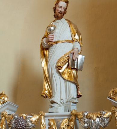 Zdjęcie nr 2: Rzeźba drążona, ustawiona na prostopadłościennym postumencie dekorowanym od przodu akantową konsolką. Prorok ustawiony frontalnie o silnie skręconej sylwetce. W prawym ręku trzyma srebrzoną puszkę, a w lewej opuszczonej w dół otwartą księgę. Twarz znacznie wydłużona o ekspresyjnym wyrazie, okolona jasnobrązowymi włosami i brodą. Ubrany jest w długą, białą suknię z kołnierzem oraz swobodnie zarzucony na plecy złocony płaszcz. Karnacja naturalistyczna, szata biała, płaszcz i detale stroju złocone, atrybuty srebrzone i złocone.