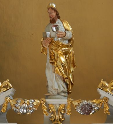 Zdjęcie nr 2: Nastawa ołtarzowa architektoniczna, jednoosiowa, dwukondygnacyjna, na cokole z bramkami. Ołtarz prostopadłościenny, drewniany; mensa drewniana. Antepedium w formie leżącego prostokąta, ujęte z trzech stron listwą o złoconym profilu, w centrum malowany złotem monogram maryjny. Tabernakulum w formie skrzynki o wklęsło-wypukłym wykroju, ustawione na profilowanym cokole, flankowane czterema kolumienkami o marmoryzowanych na niebiesko trzonach, podtrzymującymi niepełne belkowanie i wydatny gzyms. Ścianki boczne dekorowane prostokątnymi, marmoryzowanymi na niebiesko płycinami w złoconych ramach. Drzwiczki w kształcie stojącego prostokąta, zamkniętego łukiem nadwieszonym; w polu krucyfiks osadzony na wolutowej podstawie, od której odchodzą dwie gałązki akantu. Po bokach drzwiczek dwie wici roślinne. Tabernakulum flankują ustawione dwie figury aniołów.
Pierwsza kondygnacja retabulum ustawiona na cokole, ujęta parą filarów i stojących przed nimi, ustawionymi pod kątem kolumnami o kapitelach korynckich, dźwigających pełne belkowanie z wydatnym gzymsem. W polu środkowym rama w kształcie stojącego prostokąta zamkniętego trzema bokami z ośmioboku, dekorowana kampanulami, ujęta festonami z kampanulami, kwiatami i owocami. W polu obrazowym krucyfiks ukazany na malowanym tle Golgoty. Po bokach tabernakulum ustawione dwie figury: św. Jana Ewangelisty po lewej i św. Łukasza po prawej stronie.
Pośrodku belkowania zawieszone duże serce przebite sześcioma mieczami. Po jego bokach dwie rzeźby aniołków. Na gzymsie, na osi kolumny po prawej stronie ustawiona jest rzeźba św. Weroniki, a przed nią siedzący aniołek z trzema gwoździami w dłoni. Po lewej stronie św. Maria Magdalena, a przed nią aniołek z młotkiem w dłoni. 
Druga kondygnacja jest węższa, ujęta parą pilastrów i parą dostawionych pod kątem kolumn o kapitelach kompozytowych, dźwigających imposty. Cokoły kolumn i imposty ozdobione są z każdej strony uskrzydlonymi główkami aniołków. W polu rama w kształcie stojącego prostokąta o ściętych narożach, zdobiona ornamentem roślinnym, ujęta ornamentem z akantu i karbowanej wstęgi. Pośrodku promienista gloria z rzeźbioną gołębicą Ducha Świętego na tle obłoków. Całość zwieńczona drugą promienistą glorią z półpostacią Boga Ojca na tle obłoków. Po bokach na osi podpór siedzą dwie rzeźby aniołków. Obie kondygnacje ujęte są uszami utworzonymi z akantu i karbowanej wstęgi.
Bramki z przejściami w formie stojącego prostokąta o ściętych górnych narożach, zamknięte wydatnym gzymsem dźwiganym przez fragmenty pilastrów, na ich osi przerwany trójkątny przyczółek, zdobiony akantem. Przejścia flankowane figurami aniołów z arma Christi, nad bramkami figury proroków.
Struktura polichromowana na biało, ornamentyka i detale architektoniczne złocone i srebrzone.

